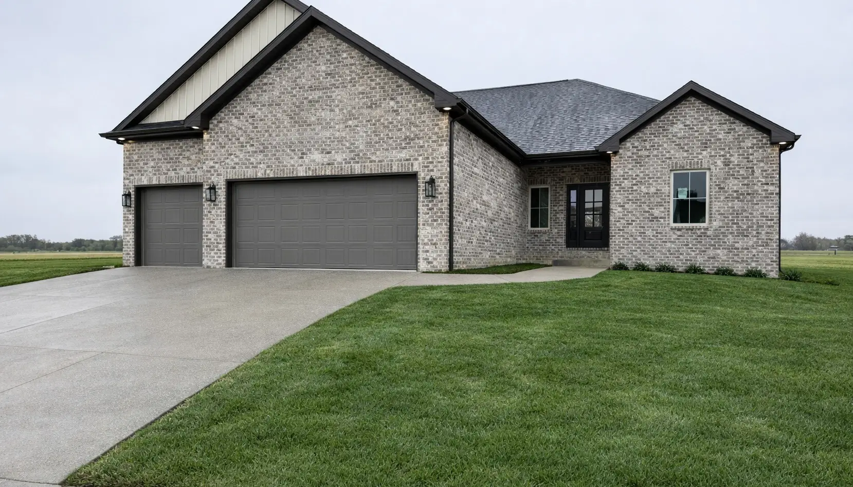 A modern Asher brick house with a dark roof, two large gray garage doors, a black front door, and a well-kept green lawn on a cloudy day