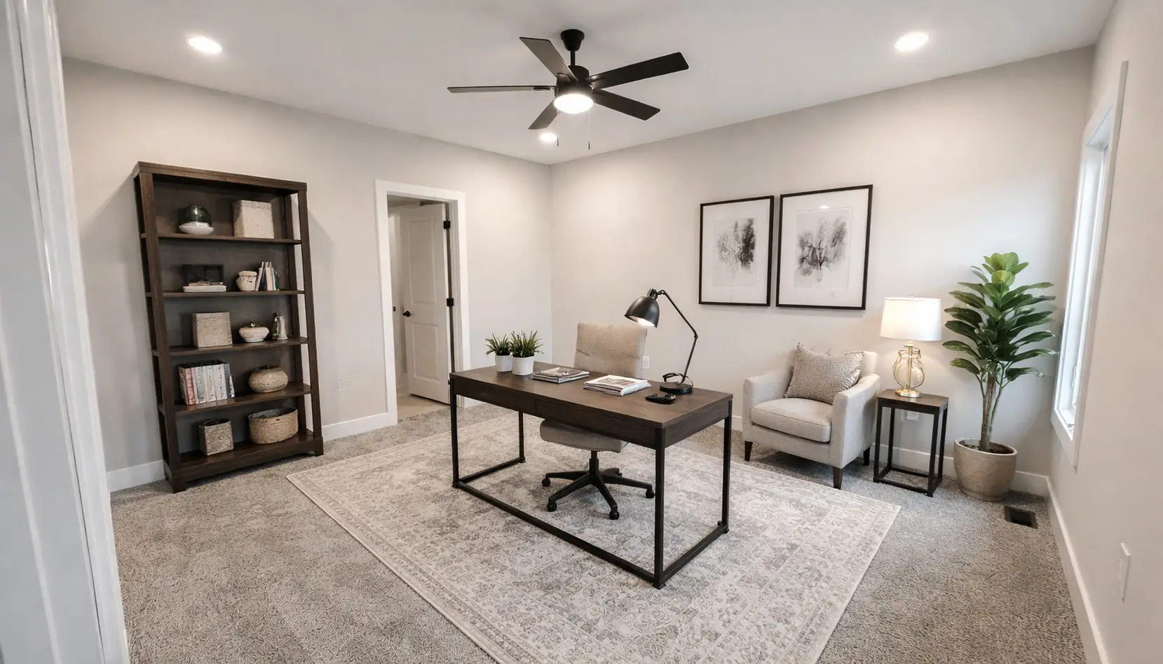 Modern home office with the sleek Asher desk, a comfortable chair, and lamp centered on a large light rug. A bookshelf, armchair, plant, and framed art decorate the neutral-toned room. Ceiling fan and recessed lights overhead