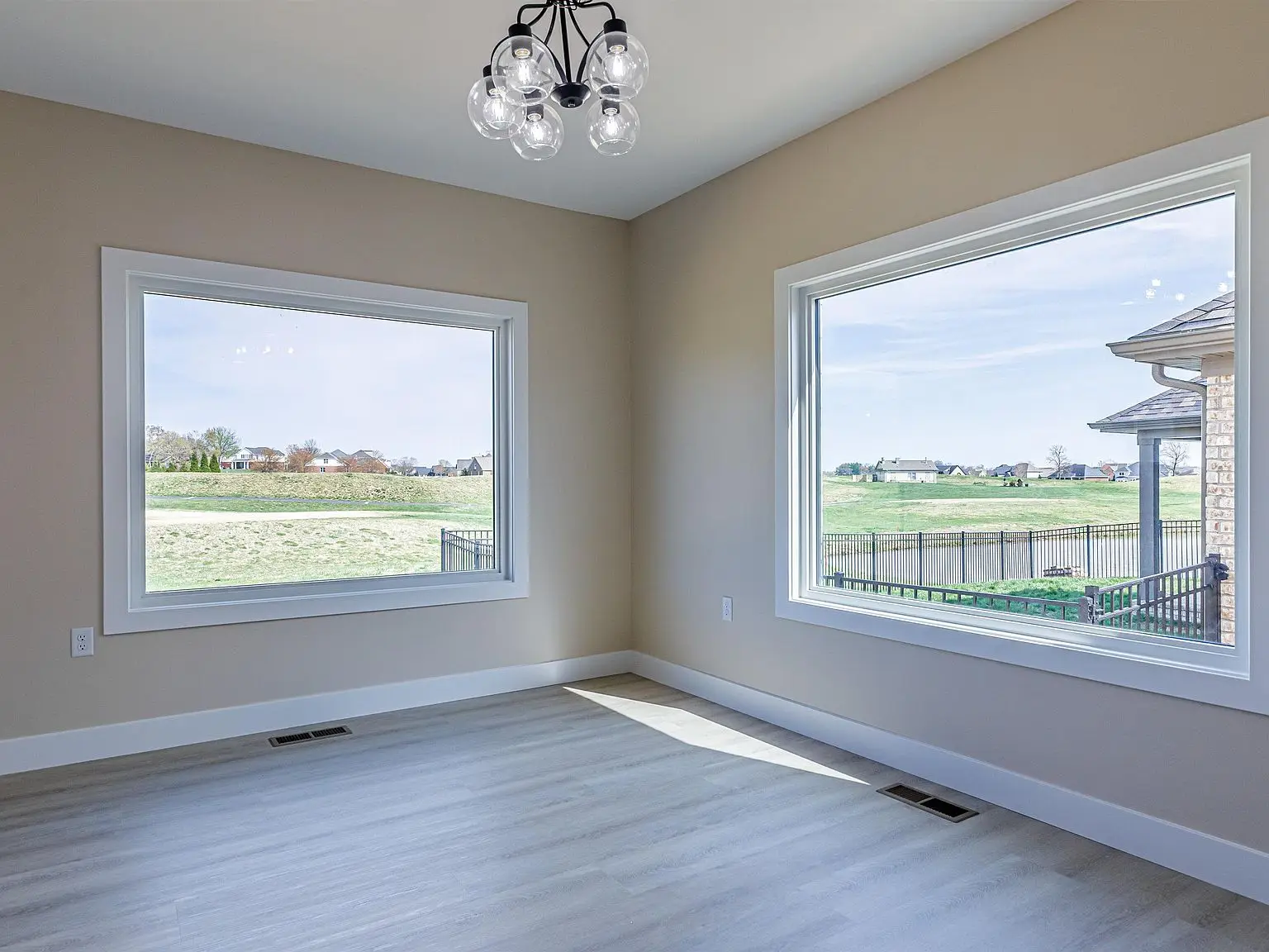 Empty room in Chris Brown Homes 18739 Roscommon Rd with wood floor and modern ceiling light fixture.
