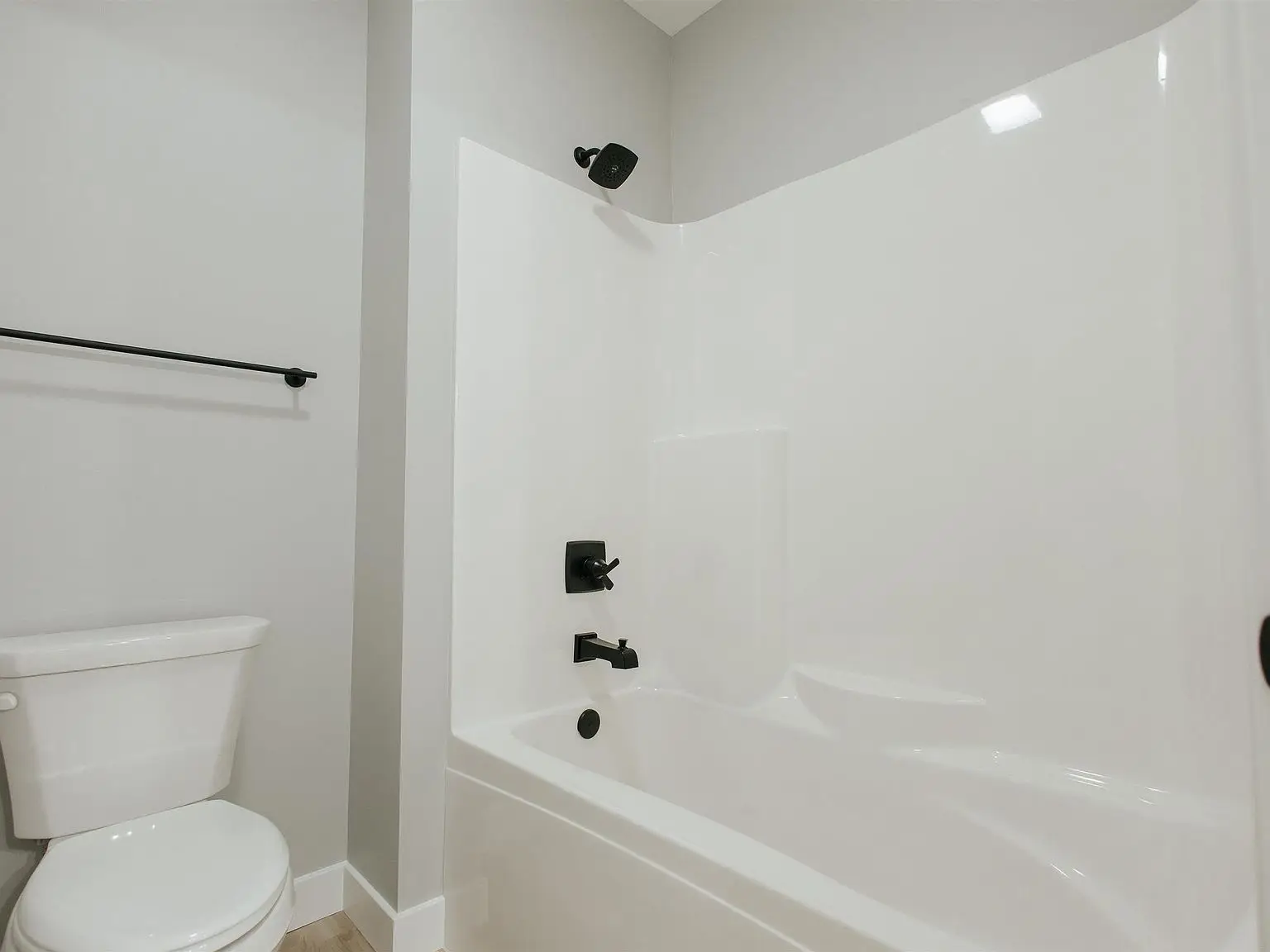 White bathtub with black fixtures in a clean Chris Brown Homes 923 Taversham Ave bathroom.