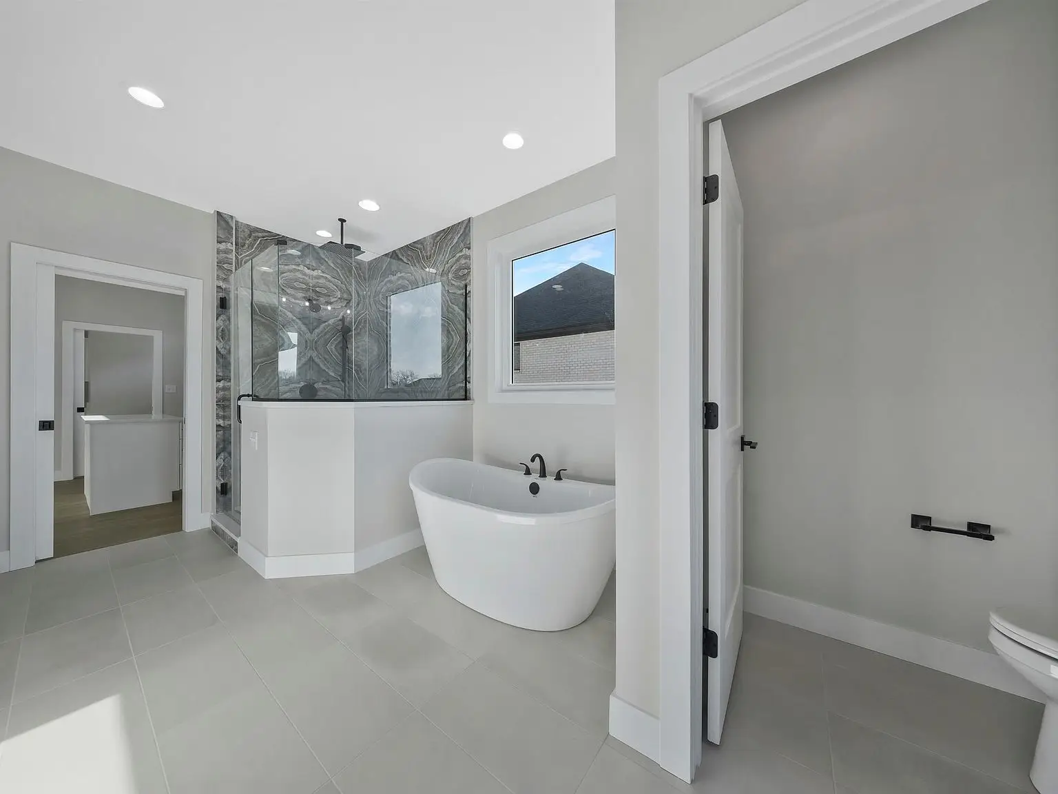 Modern bathroom in the Ava floor plan with freestanding tub, glass shower, and private toilet area.