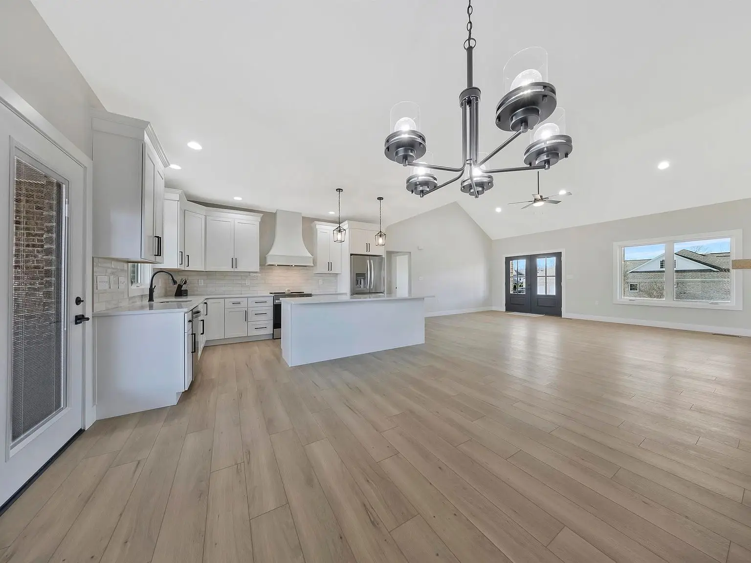 Spacious Ava floor plan kitchen and living area with light wood flooring and white cabinets.
