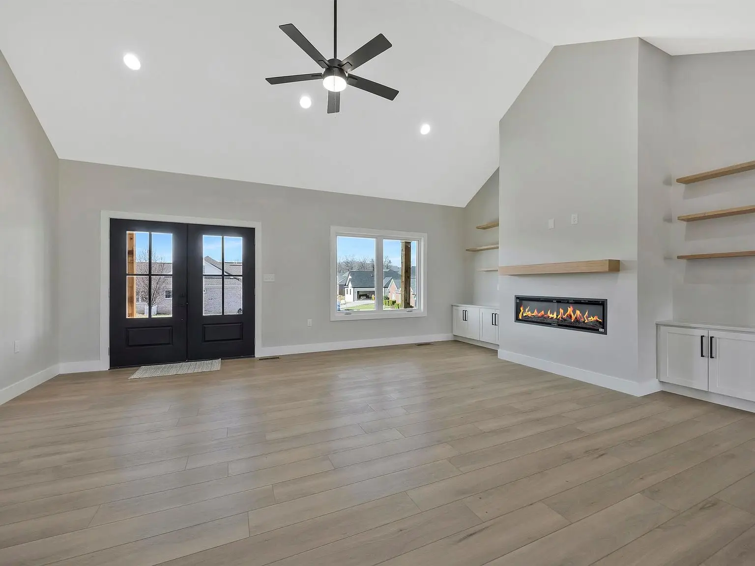 Spacious living room in the Ava floor plan with wood floors, fireplace, and built-in shelves.