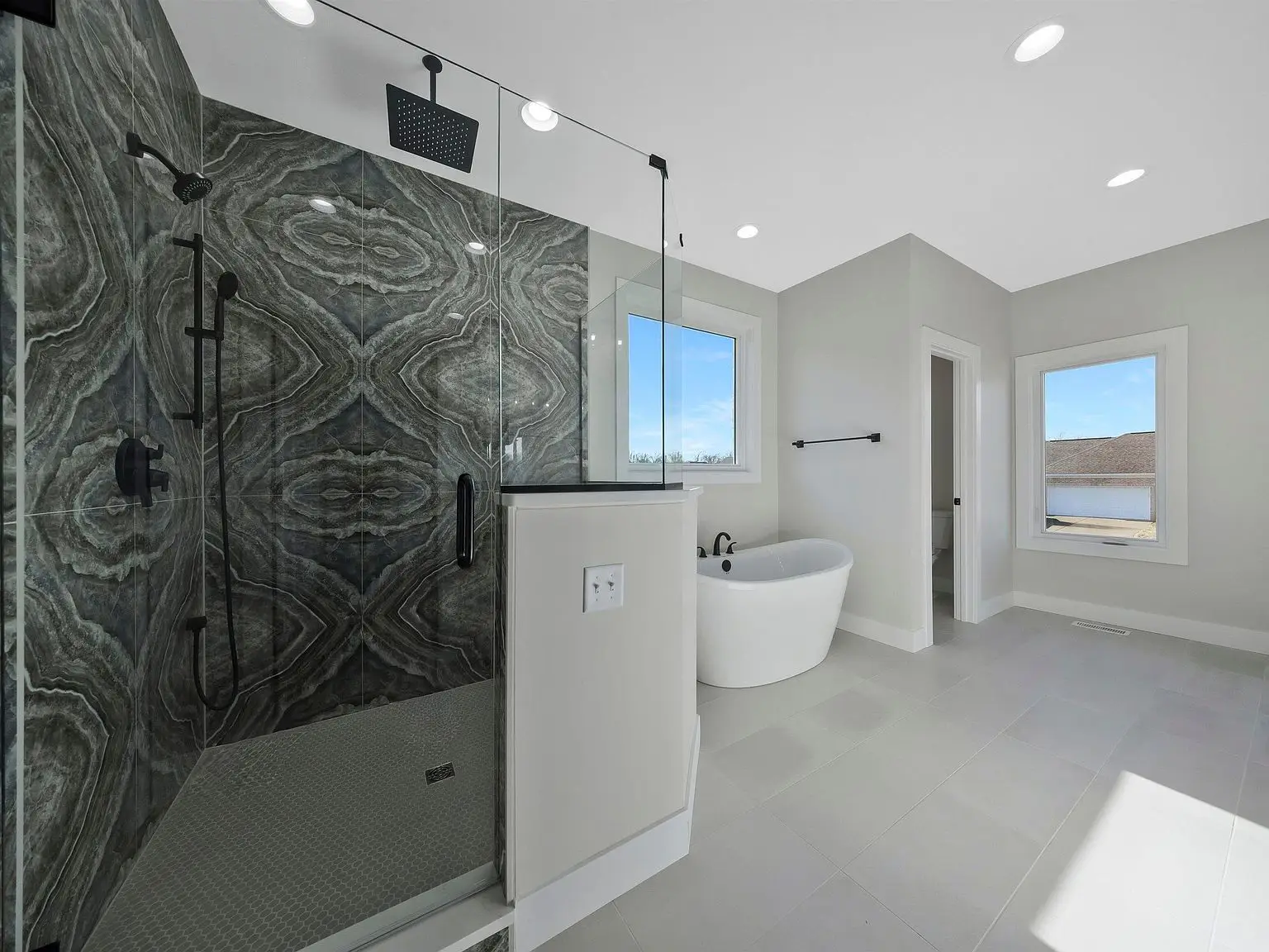 Modern bathroom in the Ava floor plan with glass shower, tub, and light tile at Chris Brown Homes.