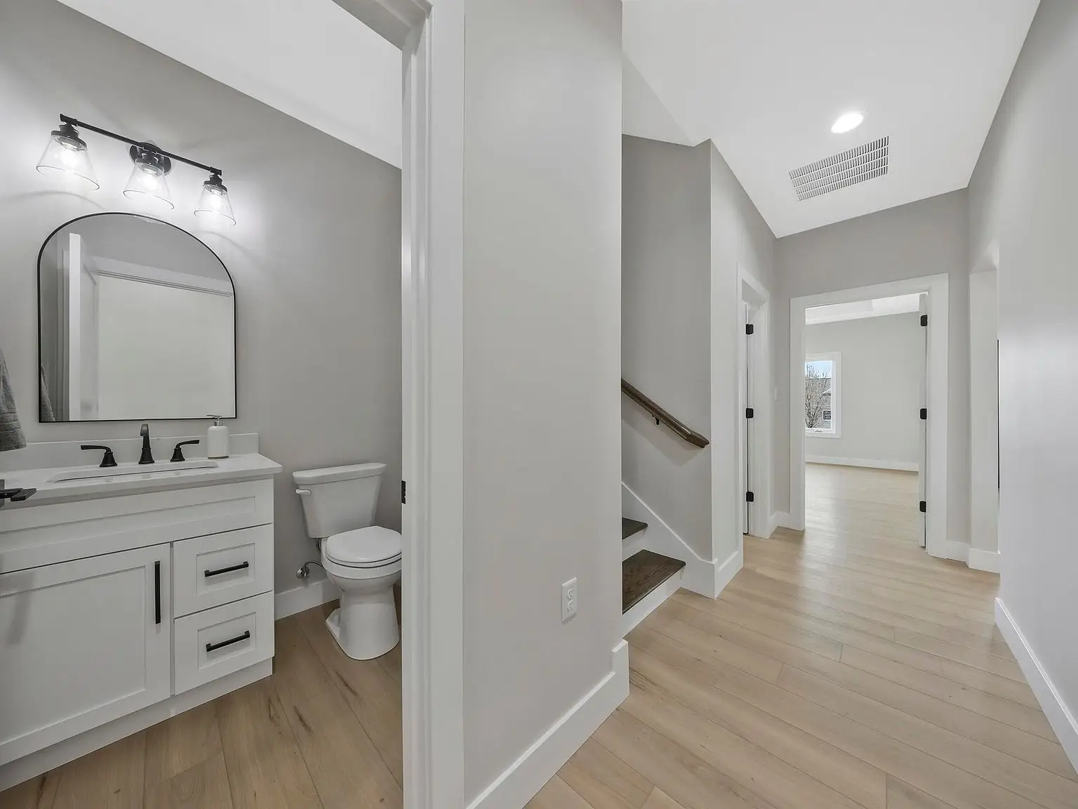 Modern hallway with light wood floors, Ava floor plan, bathroom left, staircase center.