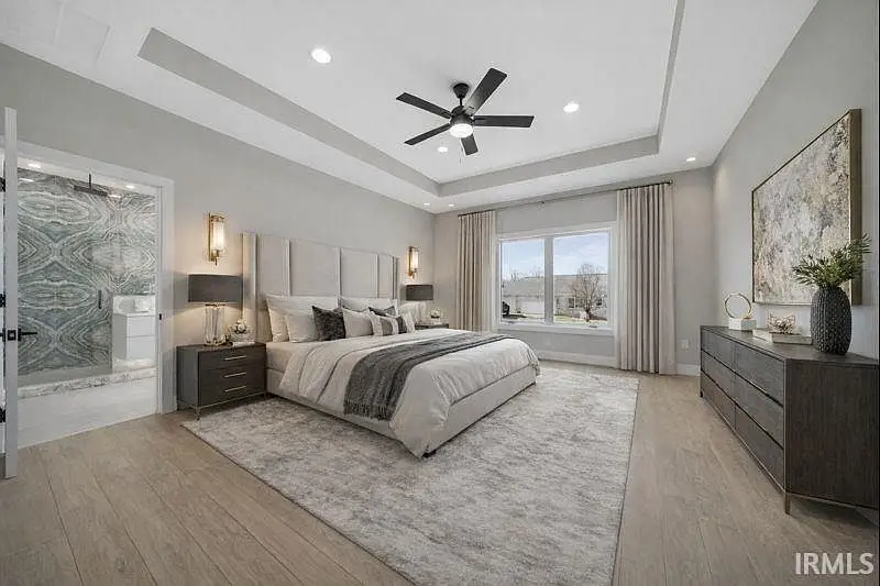 Modern Ava floor plan bedroom with large bed, wood floor, ceiling fan, and a big window.