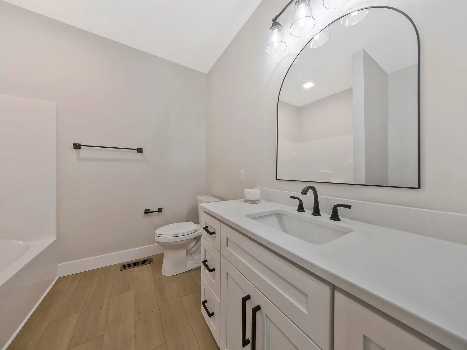 Modern bathroom in the Ava floor plan with white vanity, large mirror, and light wood floor.
