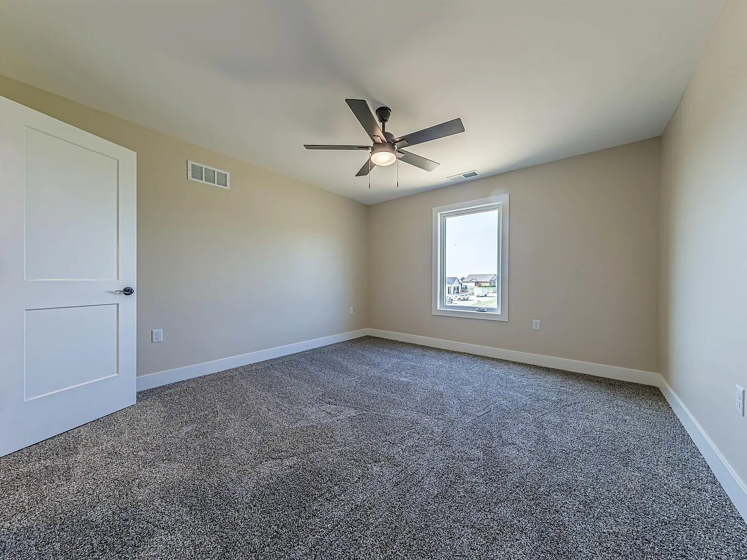 Empty bedroom in the DaVinci floor plan with gray carpet, beige walls, and a ceiling fan.