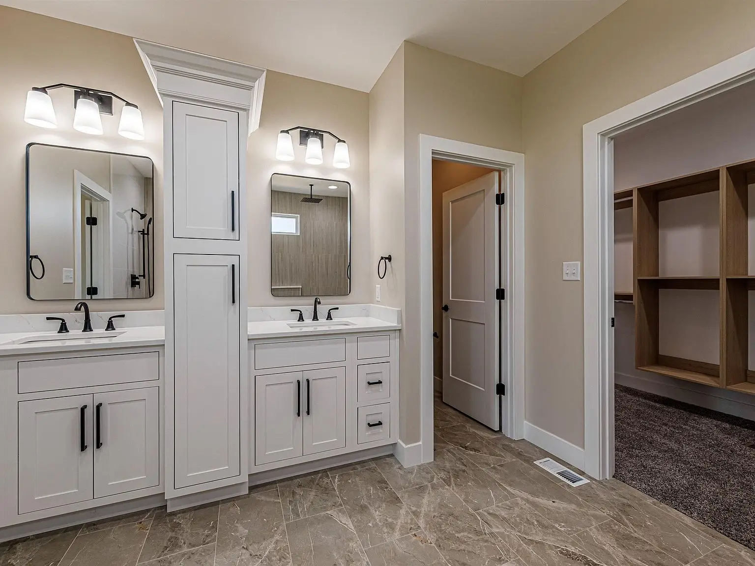 Modern bathroom in the DaVinci floor plan with double sinks, white cabinets, and beige tile floor.