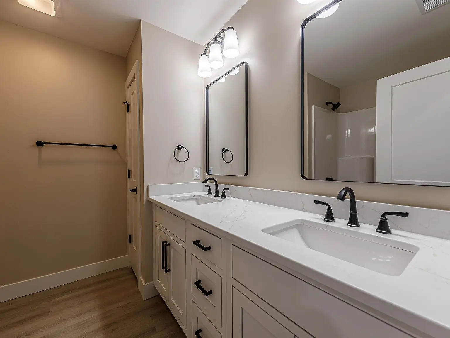 Double vanity bathroom in the DaVinci floor plan with white cabinets and black fixtures.