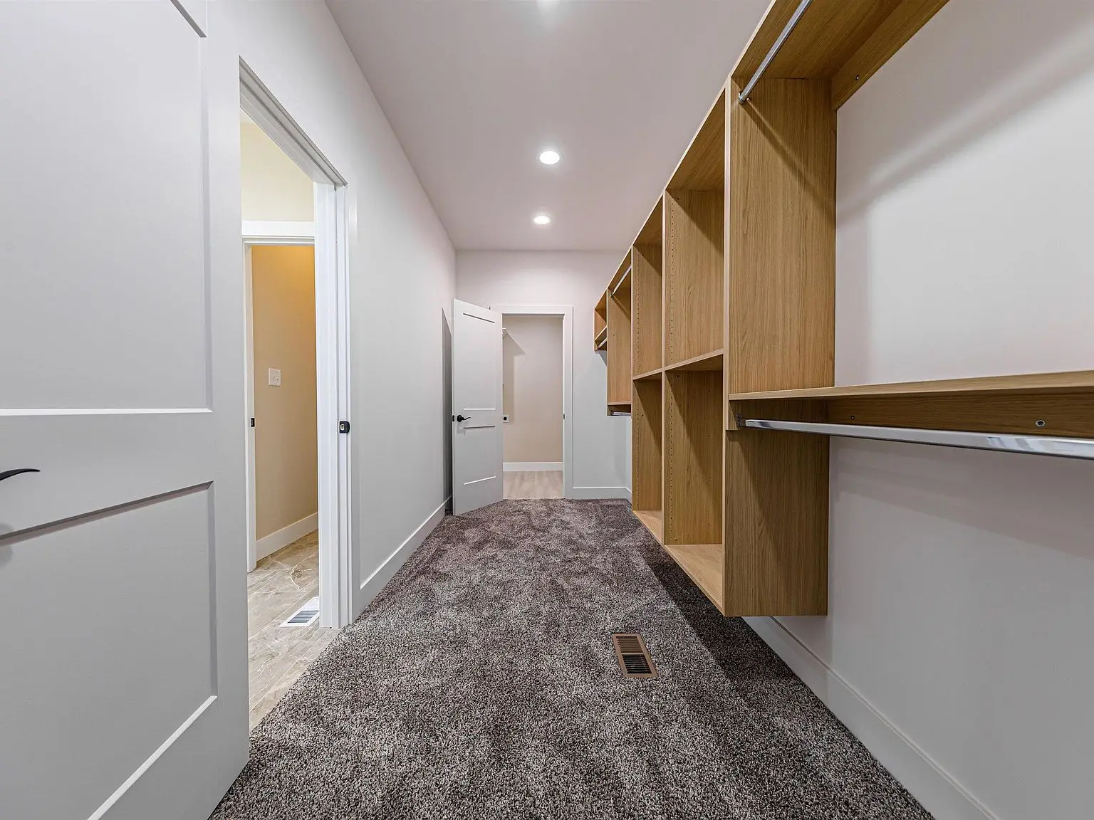 Carpeted walk-in closet with open shelves and rods in the DaVinci floor plan, white walls.