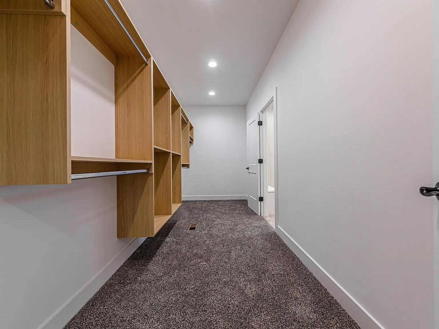 Empty walk-in closet with wooden shelves, gray carpet, part of the DaVinci floor plan.