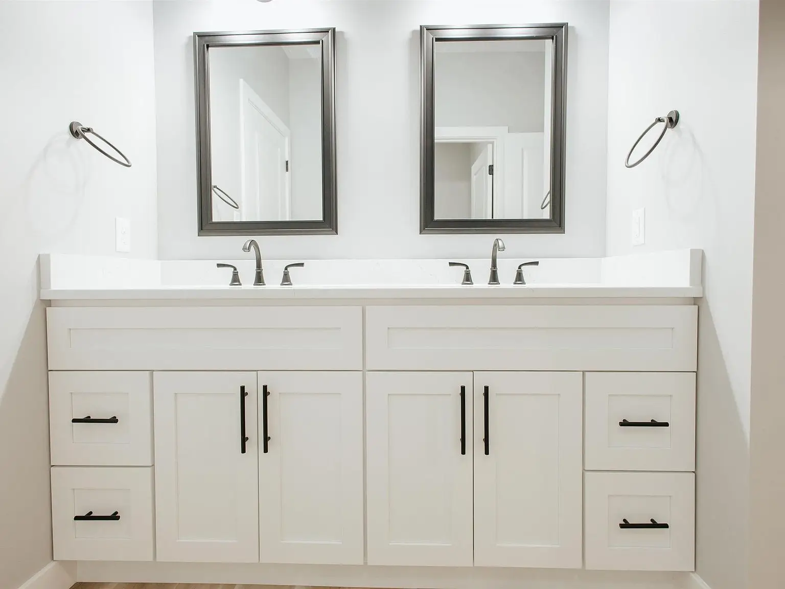 Double bathroom vanity in the Eleanor home with two sinks, mirrors, and white cabinets.
