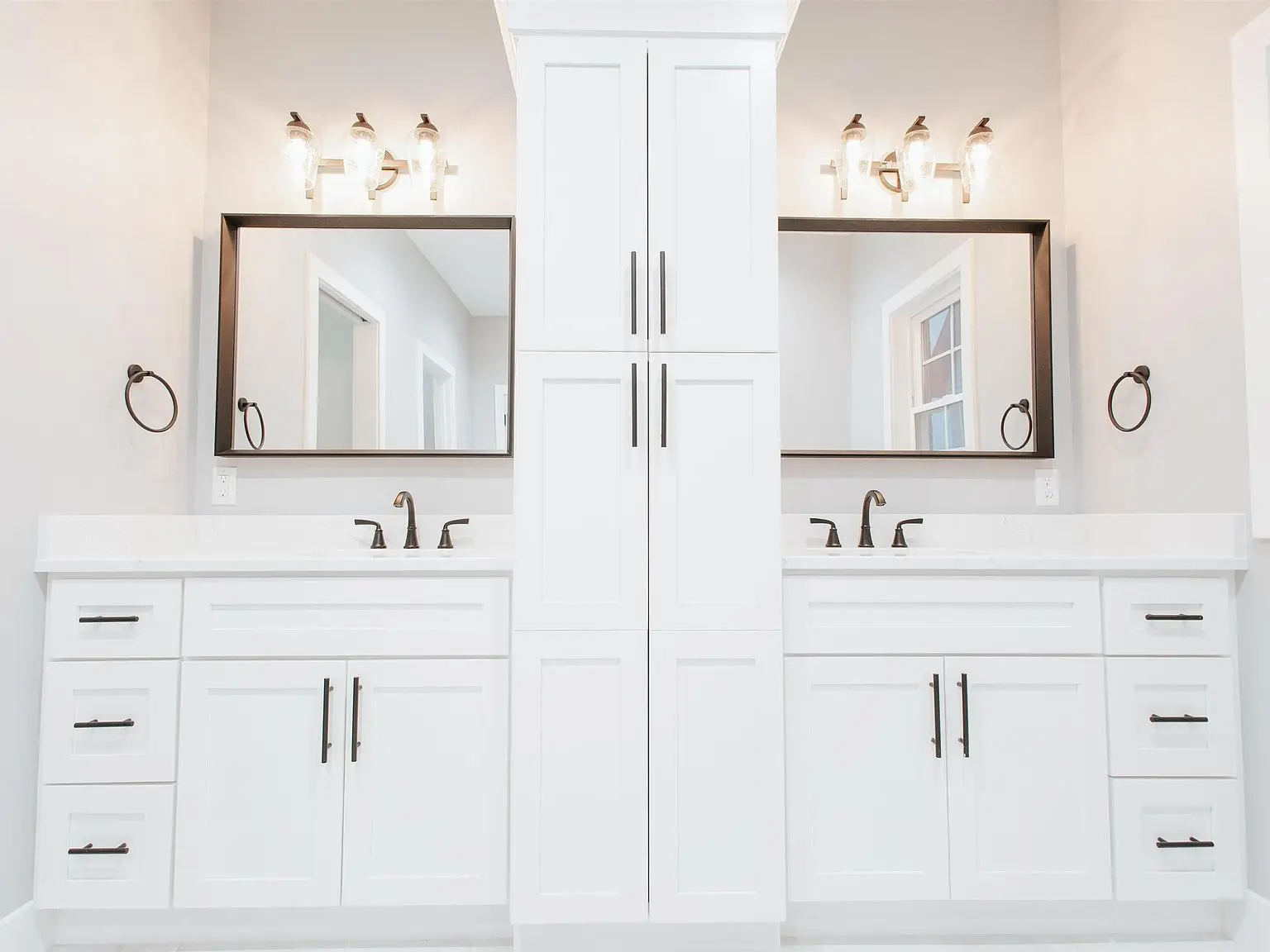 Dual sink white vanity from the Chris Brown Homes Eleanor floor plan, with mirrors and wall lights.