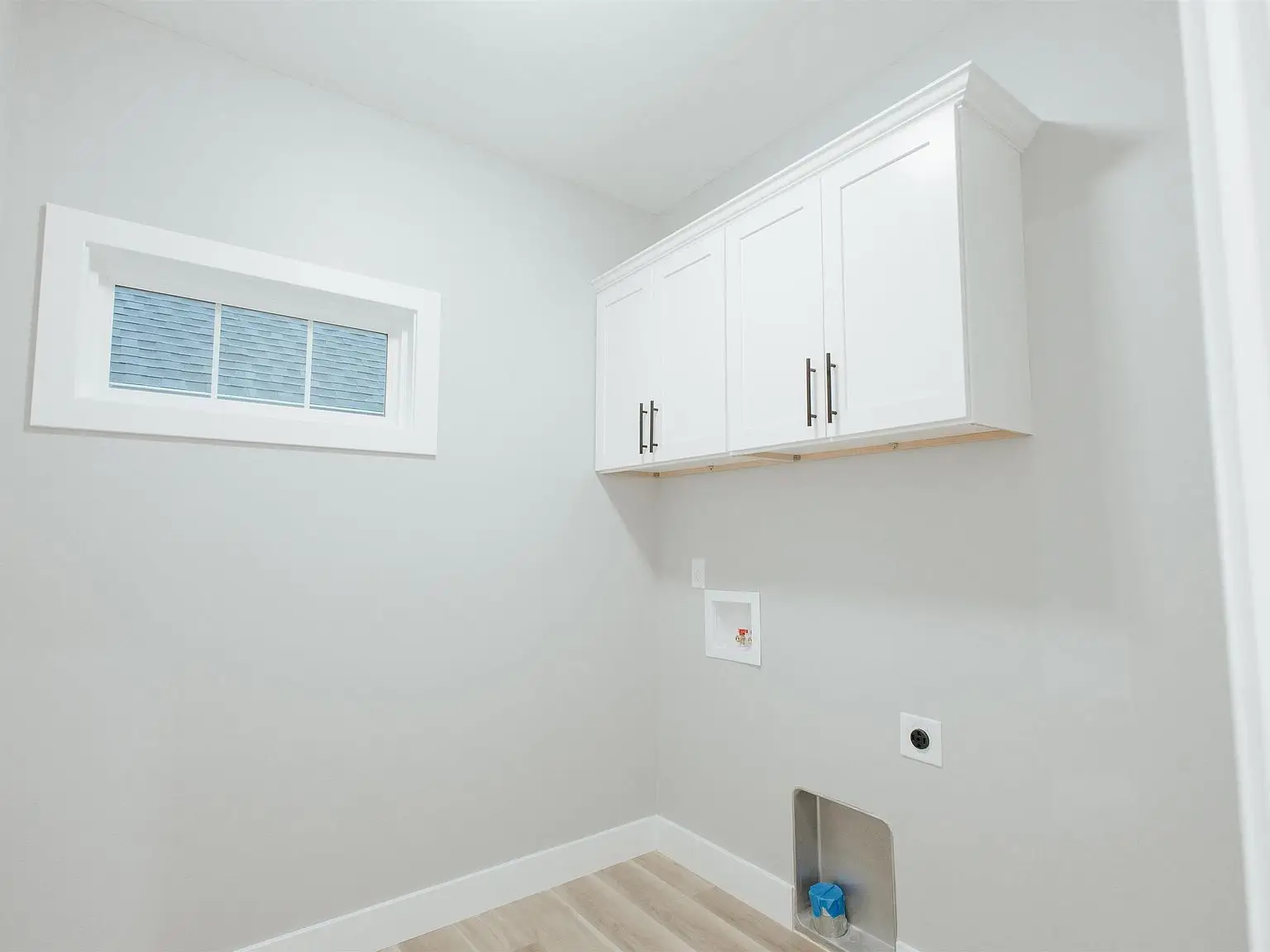 Laundry room in the Eleanor floor plan with white cabinets, hookups, and a small window.