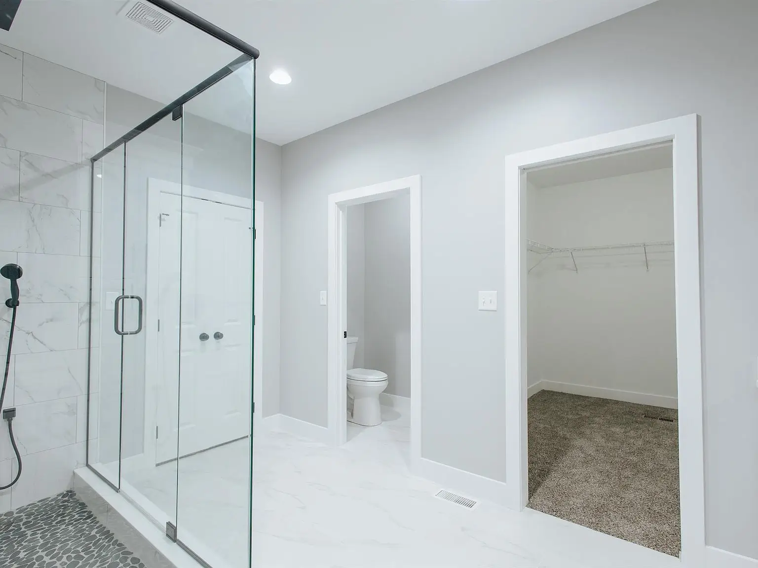 Modern bathroom in the Eleanor floor plan with glass shower and walk-in closet with wire shelving.