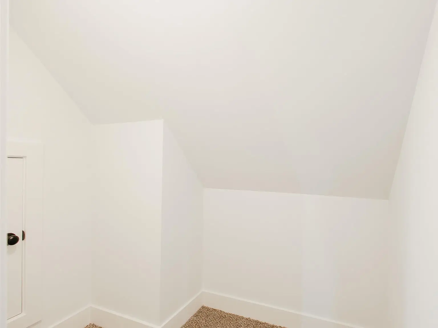 Small white room with slanted ceiling, beige carpet—part of the Eleanor floor plan.