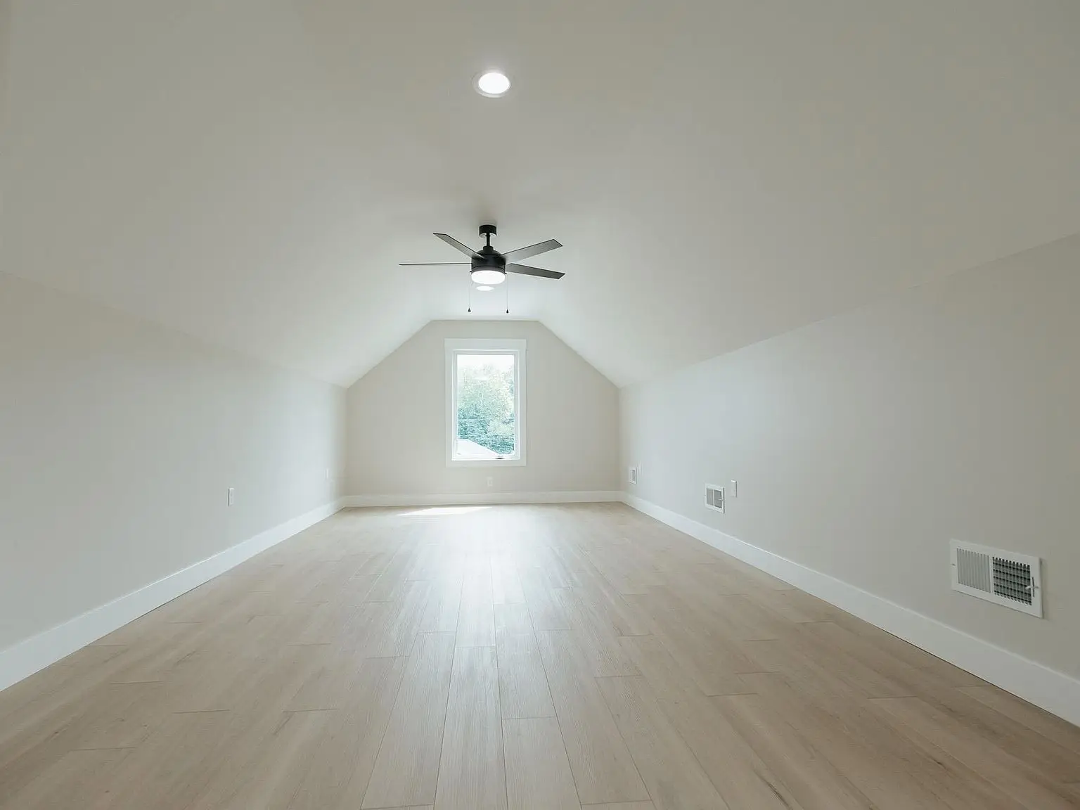 Empty attic room with light wood floor, sloped ceiling, window, and ceiling fan in Harper home.