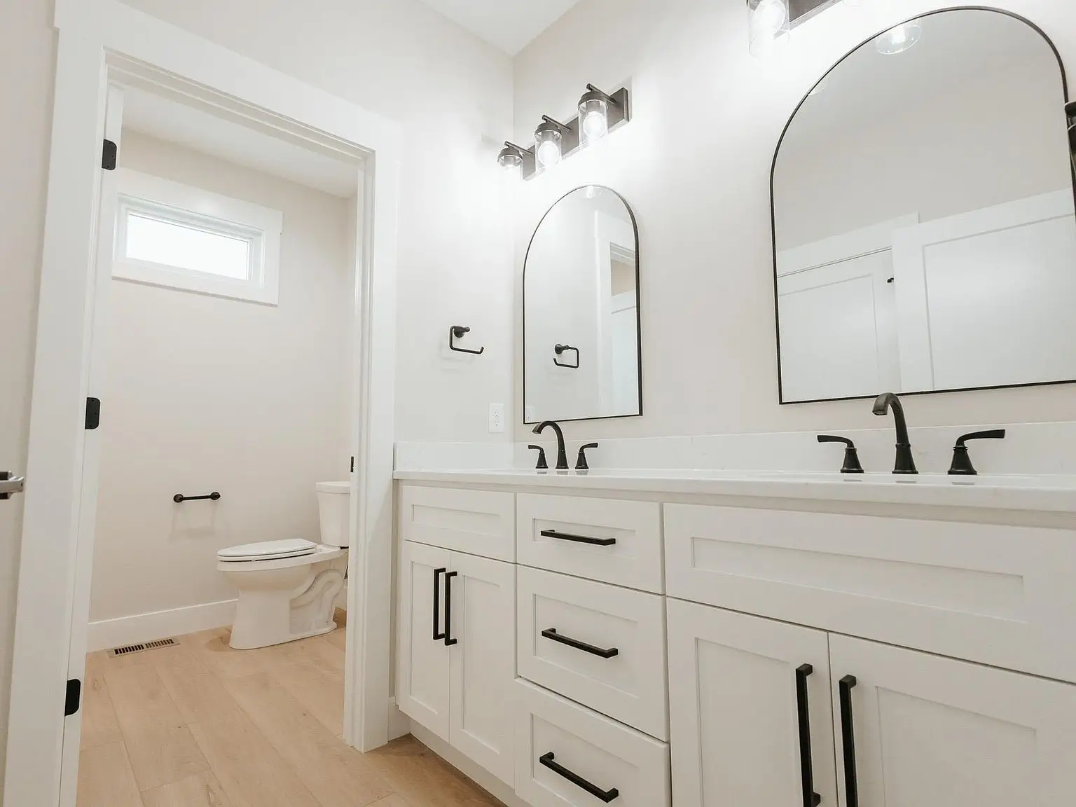 White bathroom with double sink vanity, black fixtures, in the Harper home’s private alcove.