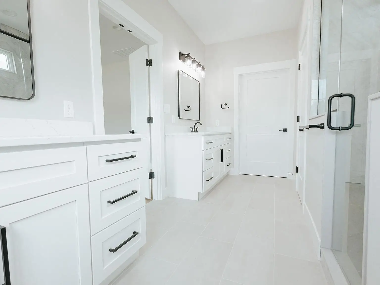 Modern white bathroom in the Harper home features double sinks and a sleek glass shower enclosure.