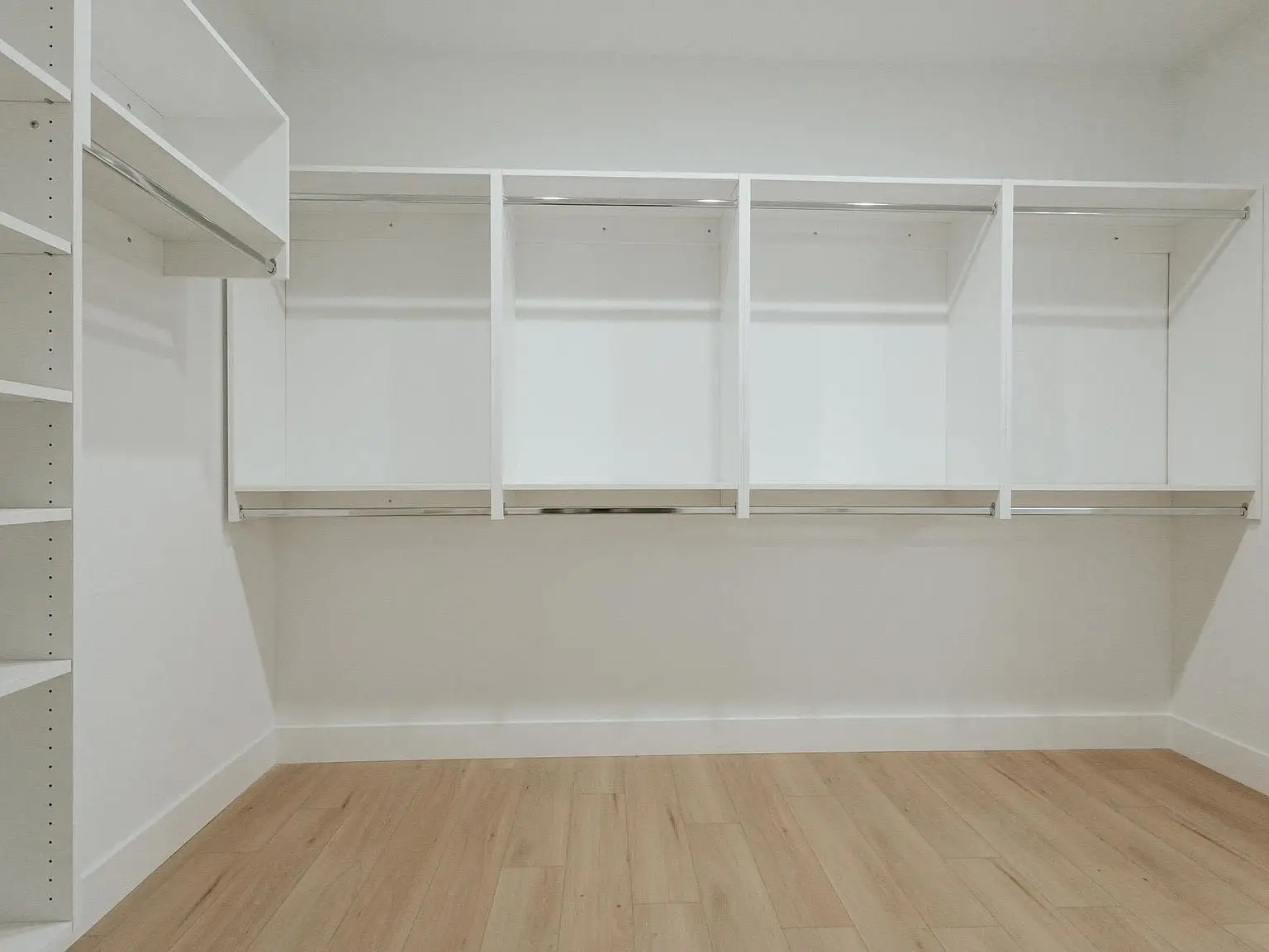 Spacious Harper floor plan walk-in closet with shelves, rods, and light wood flooring.