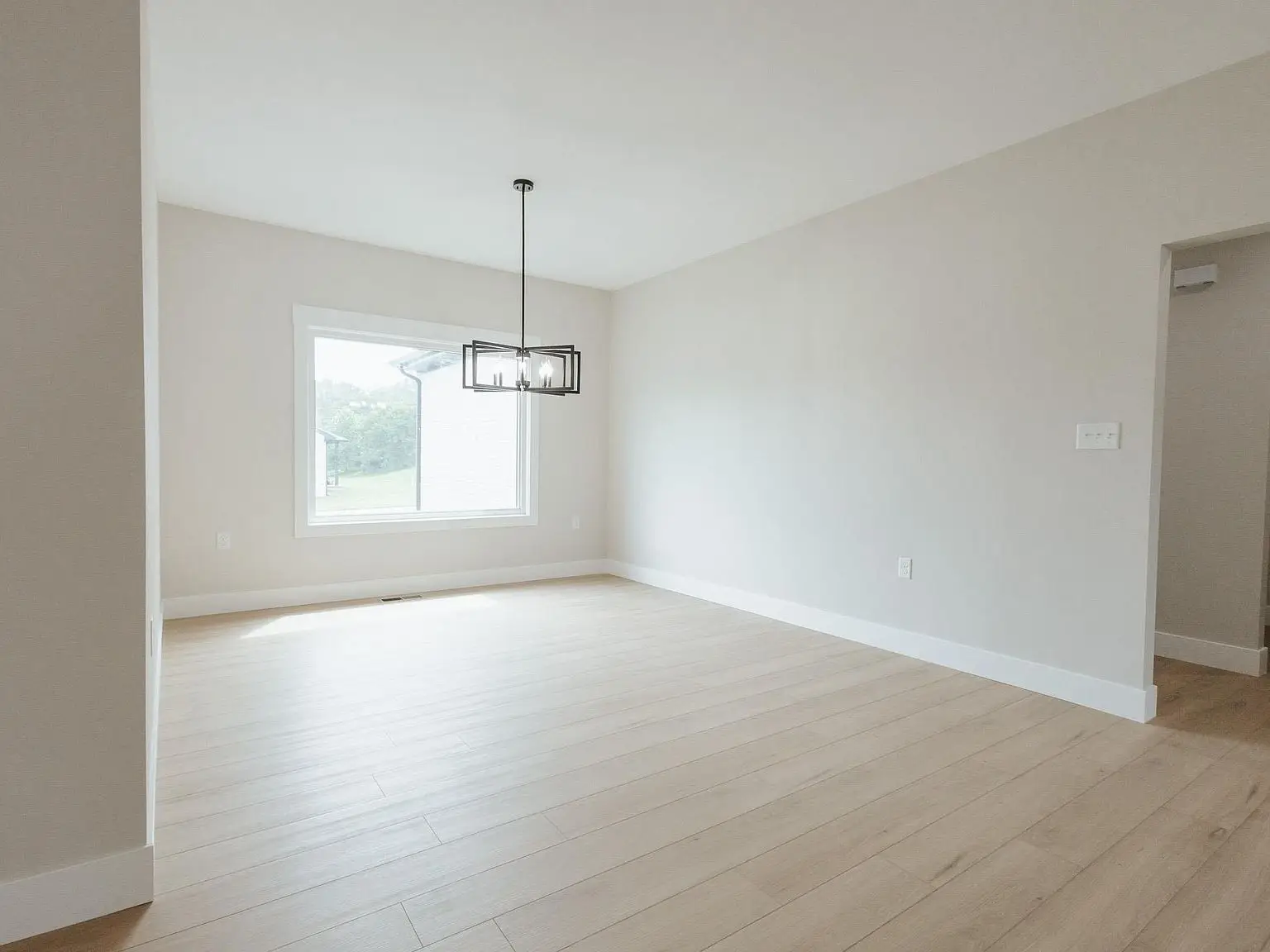 Empty room with light wood flooring, white walls, and a window in the Harper floor plan.