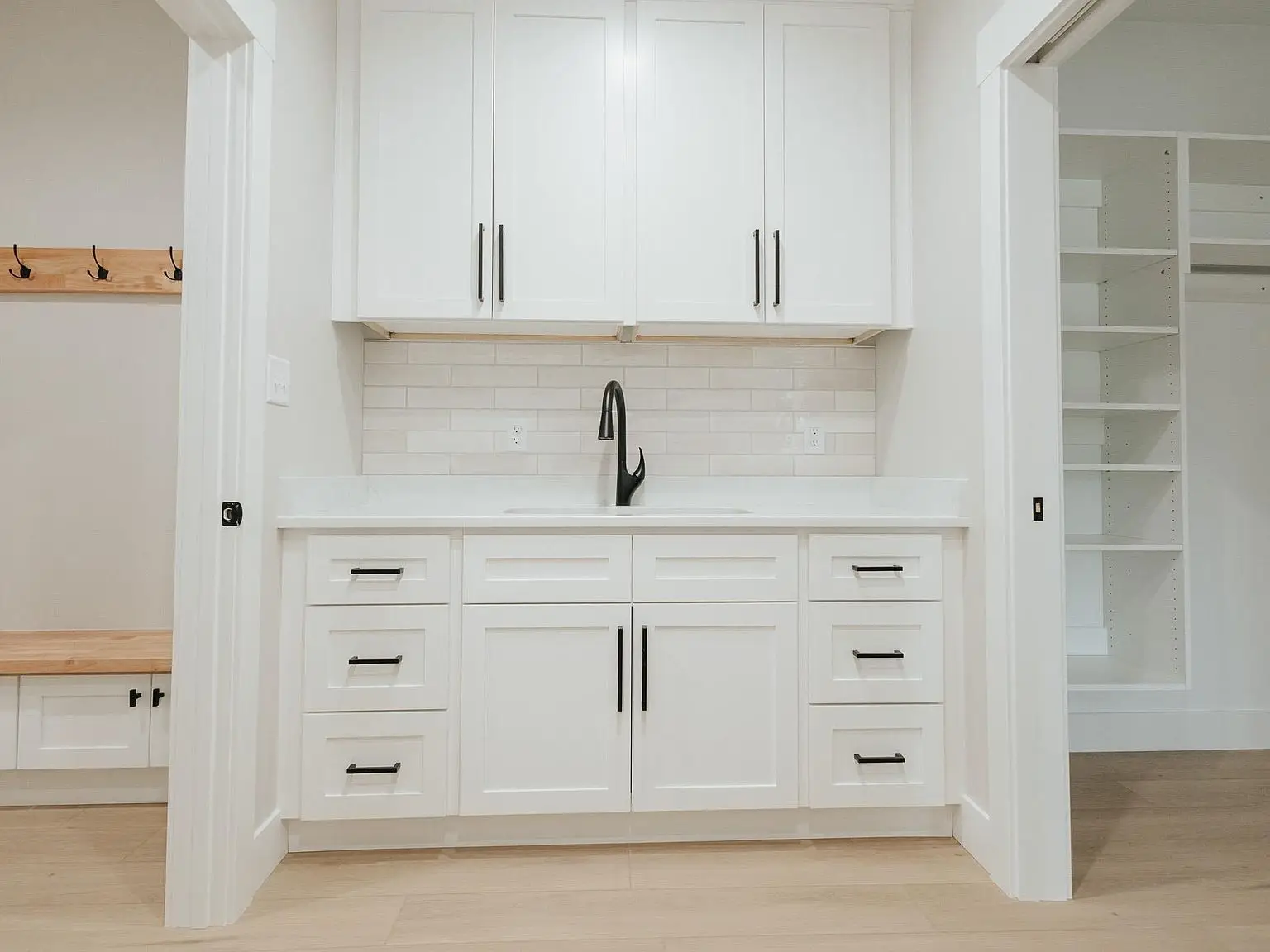 White cabinetry with black handles in a modern laundry room, featured in the Harper floor plan.