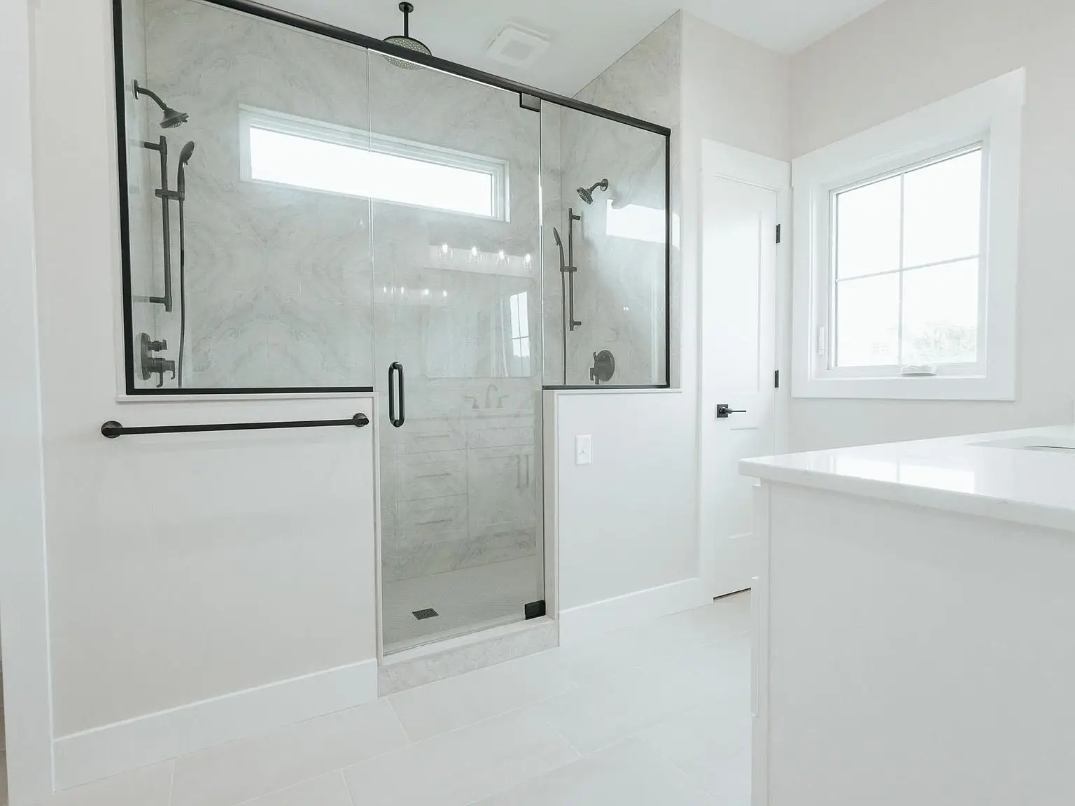 Modern bathroom in the Harper floor plan with glass shower, white walls, and right-side window.