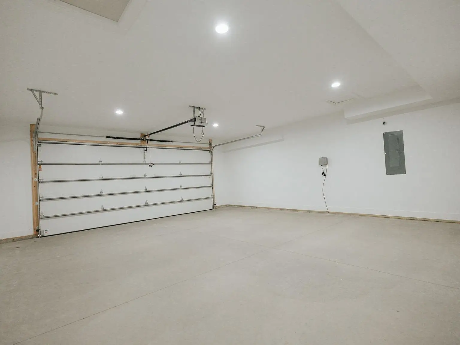 Spacious two-car garage in the Harper floor plan, featuring white walls and ceiling lights.