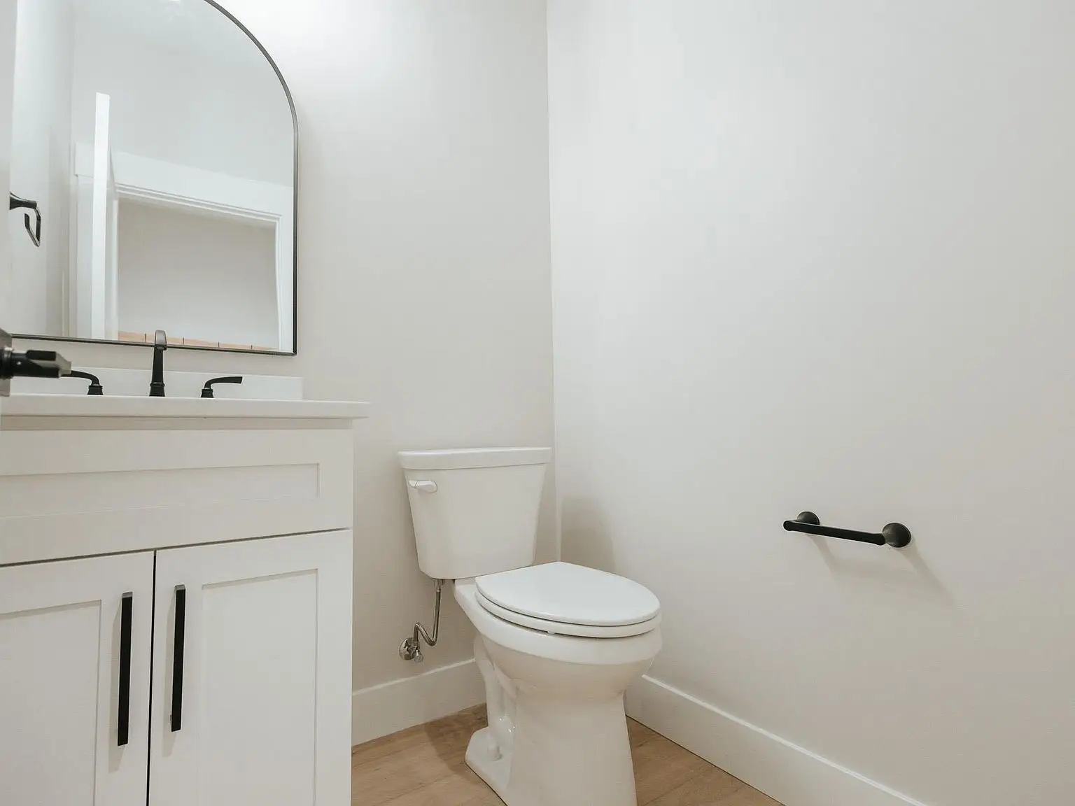 This modern bathroom in the Harper home features a white vanity, black fixtures, and a toilet.