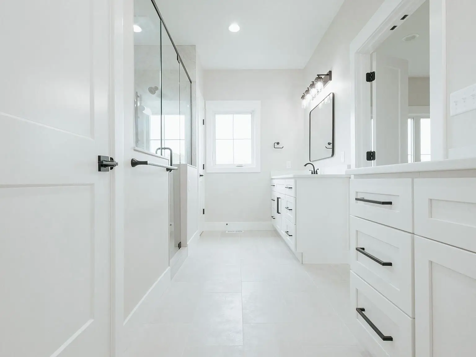 Modern white bathroom in the Harper home with double sinks, glass shower, and natural light.
