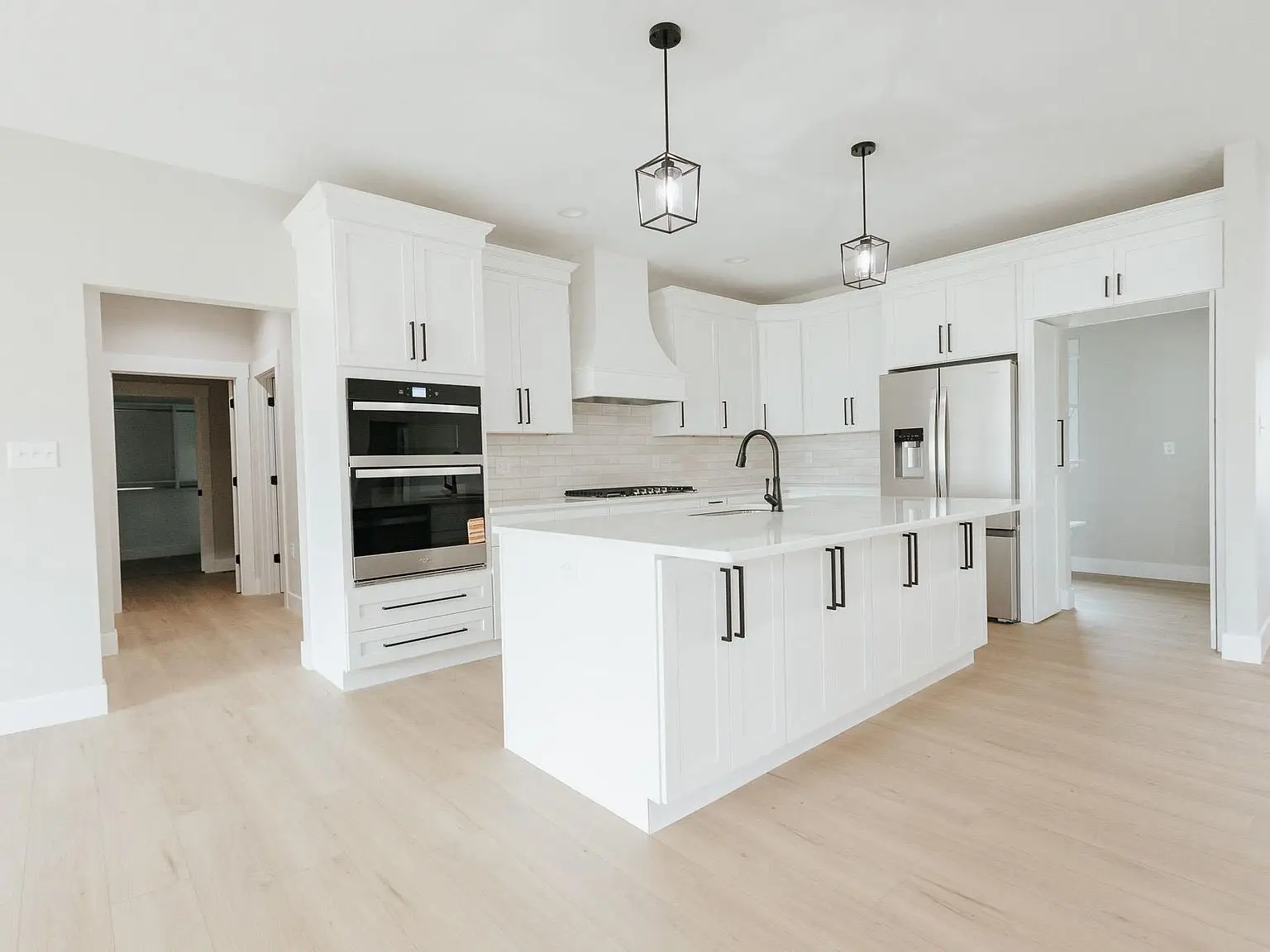 Modern Harper home kitchen with white cabinets, island, stainless appliances, and wood floors.