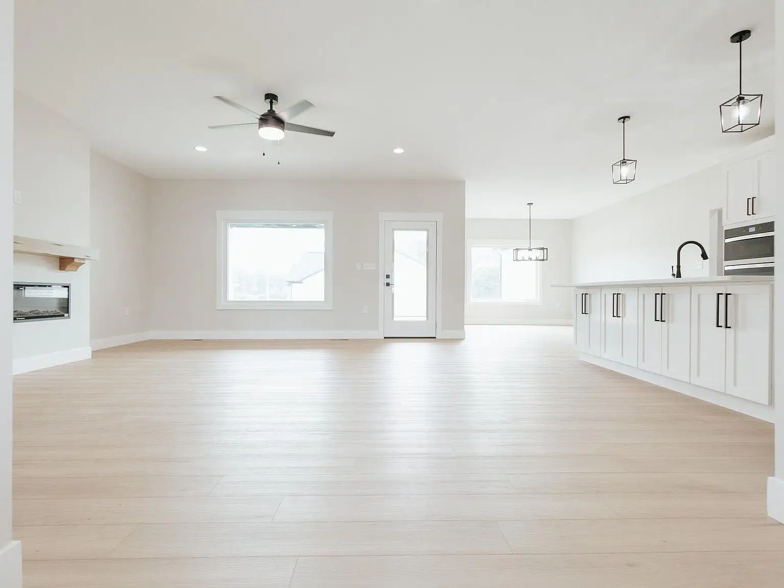Spacious modern open-plan kitchen in the Harper home with light wood floors and white walls.