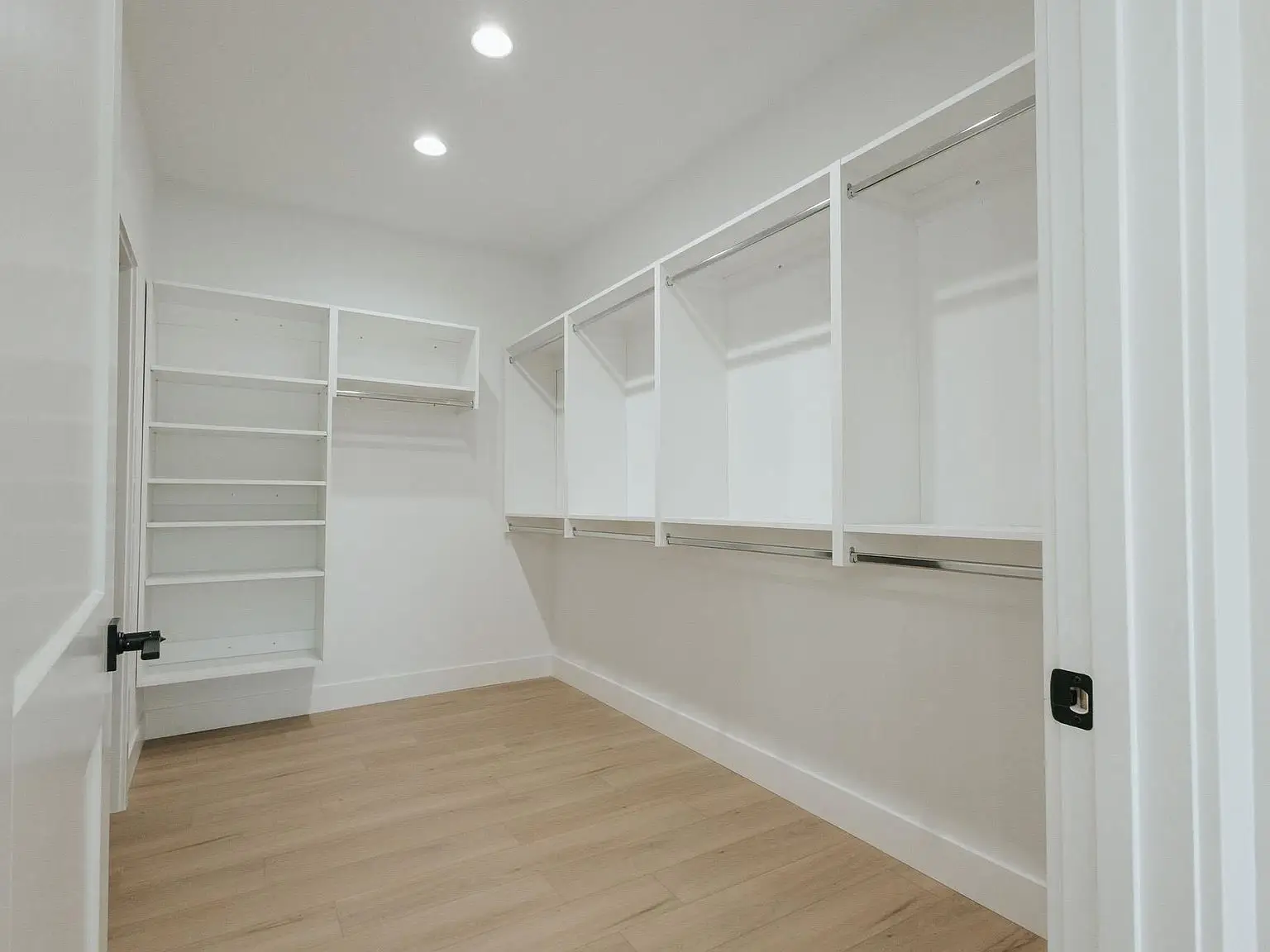 Spacious Harper home walk-in closet with white shelves, rods, wood floors; bright and airy.