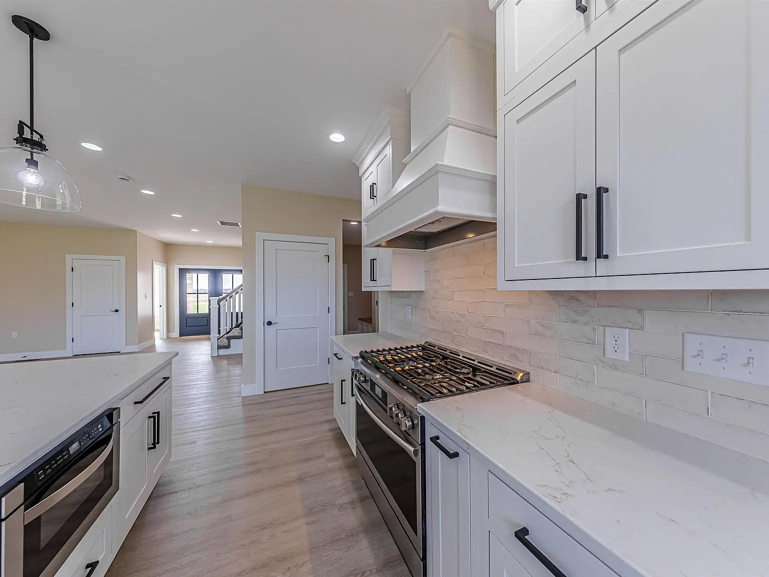 Modern kitchen with white cabinets, DaVinci floor plan, island, and light wood flooring.