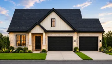 Modern suburban house with light brick exterior, black front door, two black garage doors, manicured lawn, shrubs, and a clear blue sky with soft clouds in the background. A robin perches nearby, adding a lively touch to the peaceful scene.