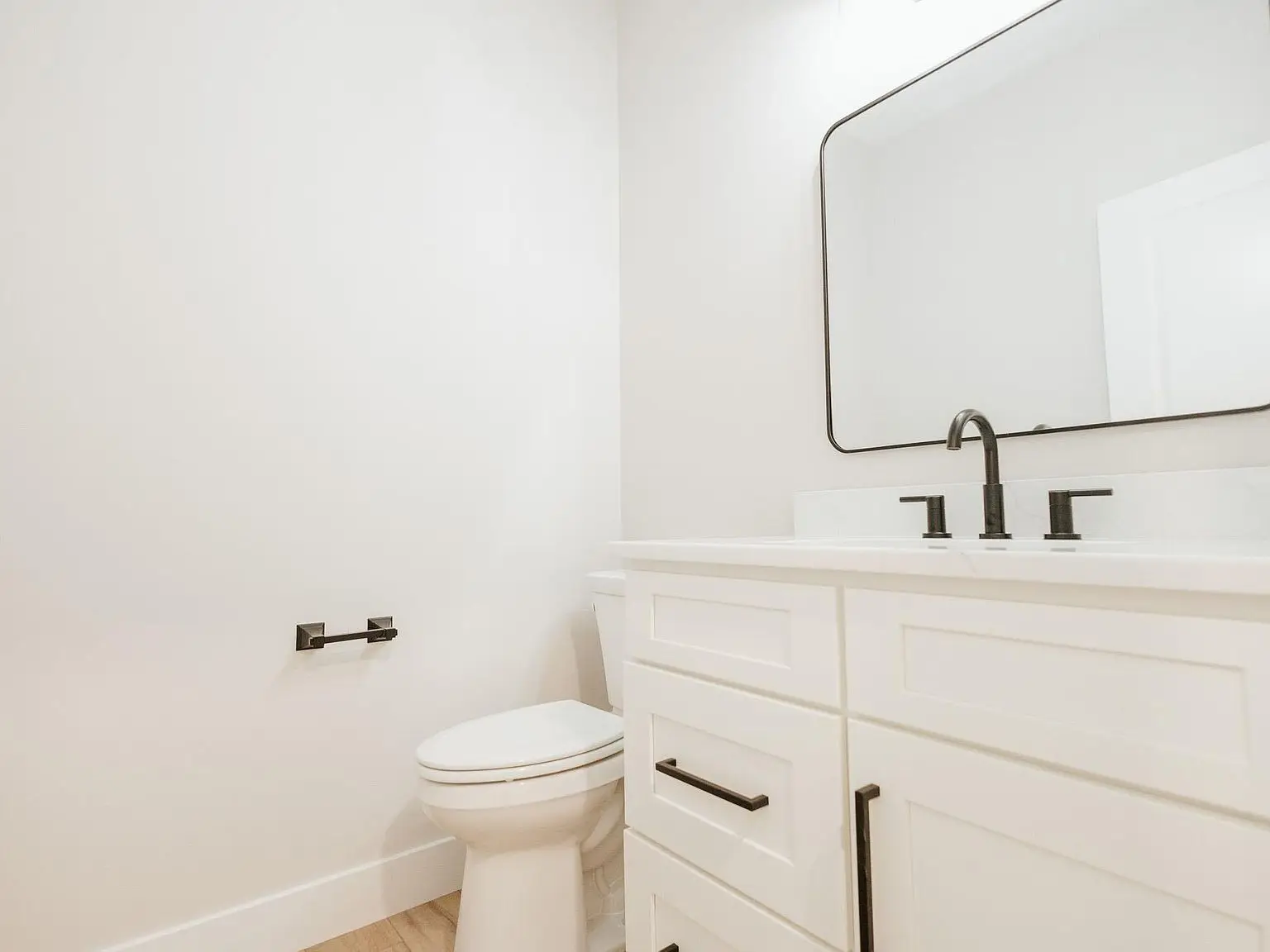 White bathroom with Asher floor plan, toilet, vanity with black fixtures, and large mirror.