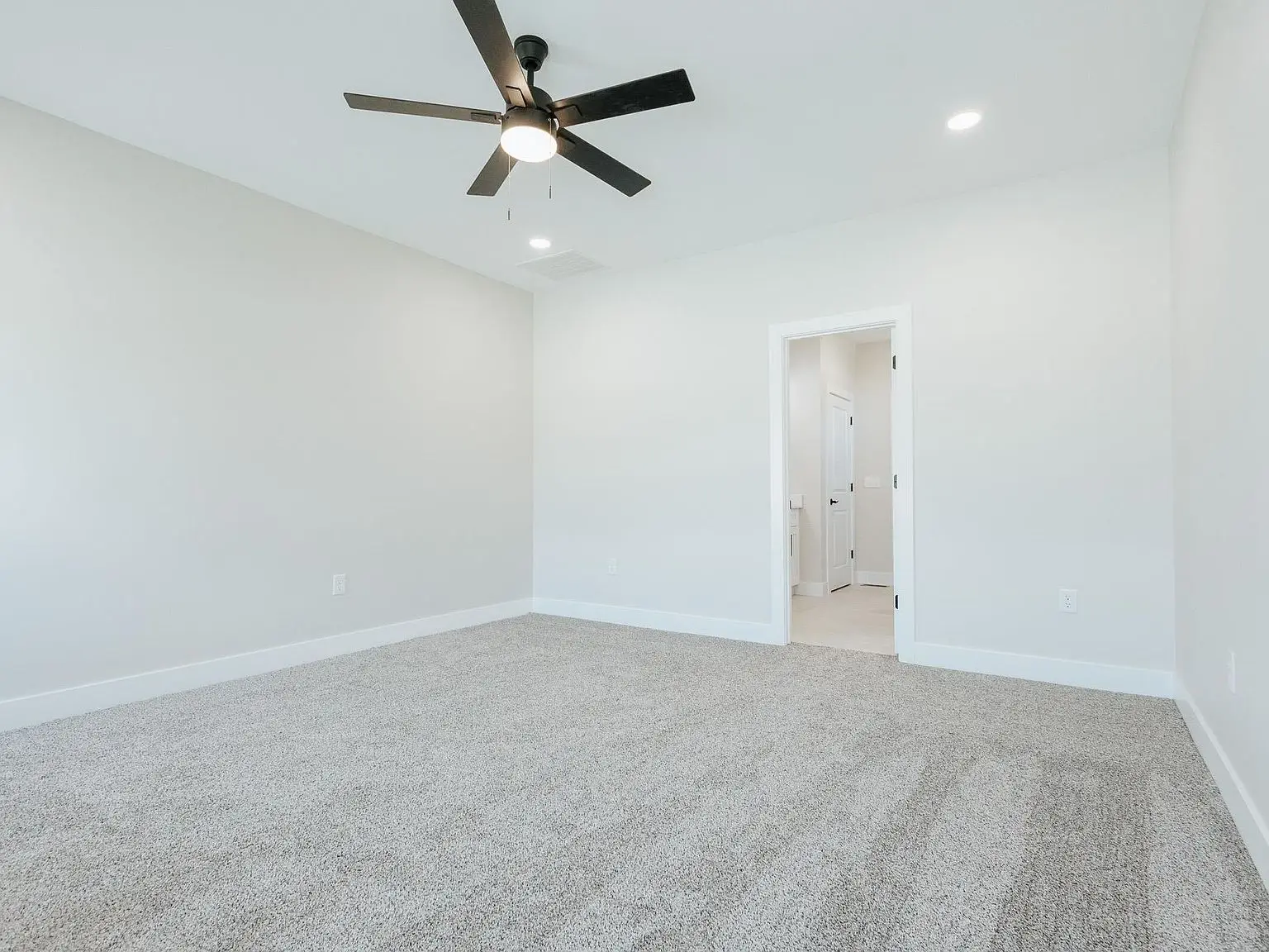Empty bedroom in Asher floor plan by Chris Brown Homes 18801 Roscommon Rd, light carpet, fan.