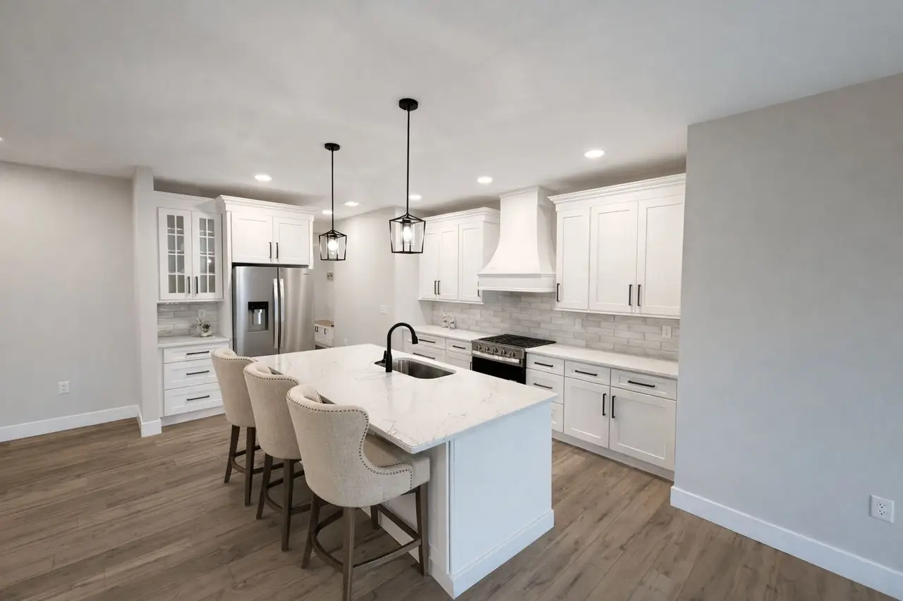 Modern kitchen featuring the Asher floor plan, white cabinets, island, and wood flooring.