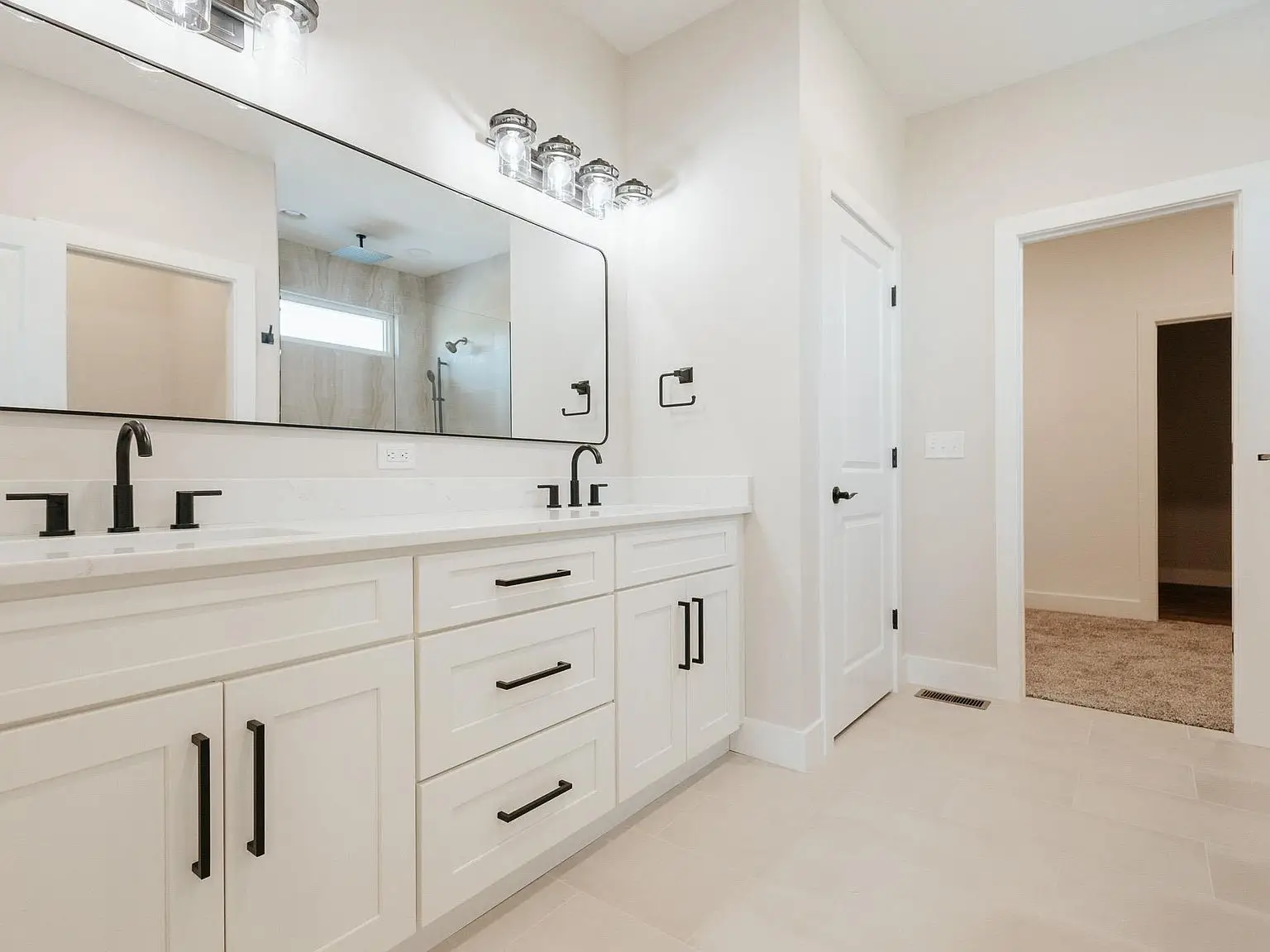 Modern bathroom in the Asher floor plan with double sinks, white cabinets, and black fixtures.