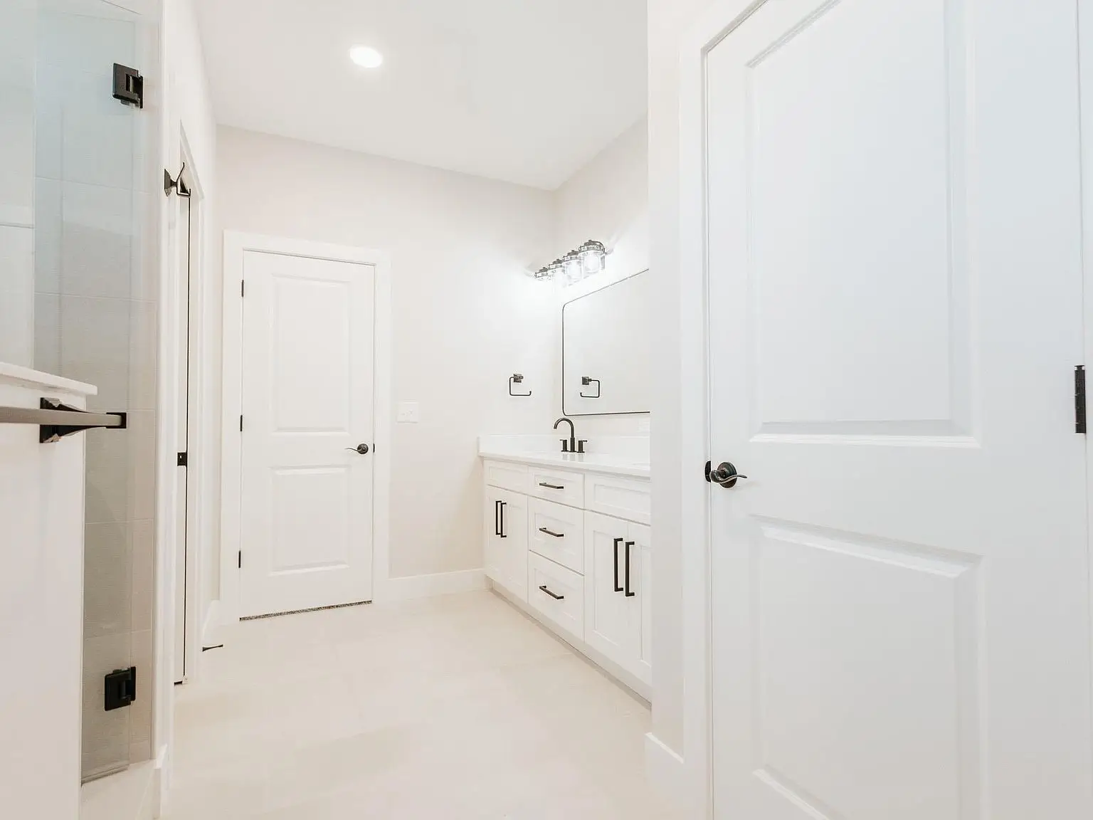 White bathroom in the Asher floor plan with double vanity, large mirror, and two white doors.