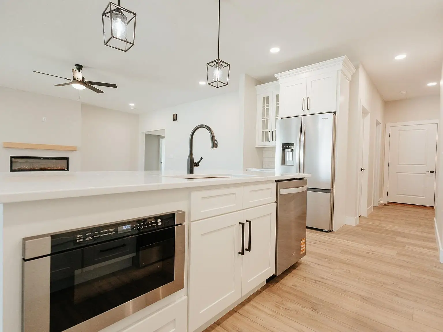 Modern Asher kitchen with white cabinets, island sink, and light wood flooring throughout.