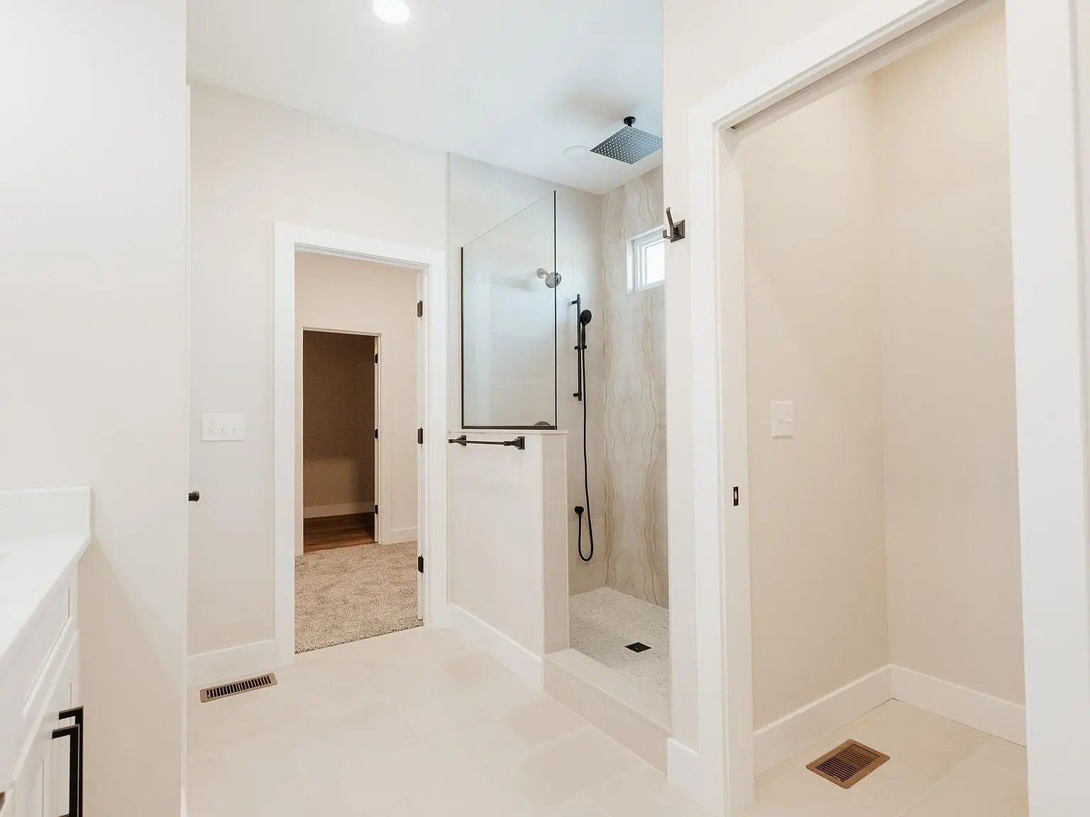 Modern bathroom in the Asher floor plan with walk-in shower, white tiles, and open hall door.