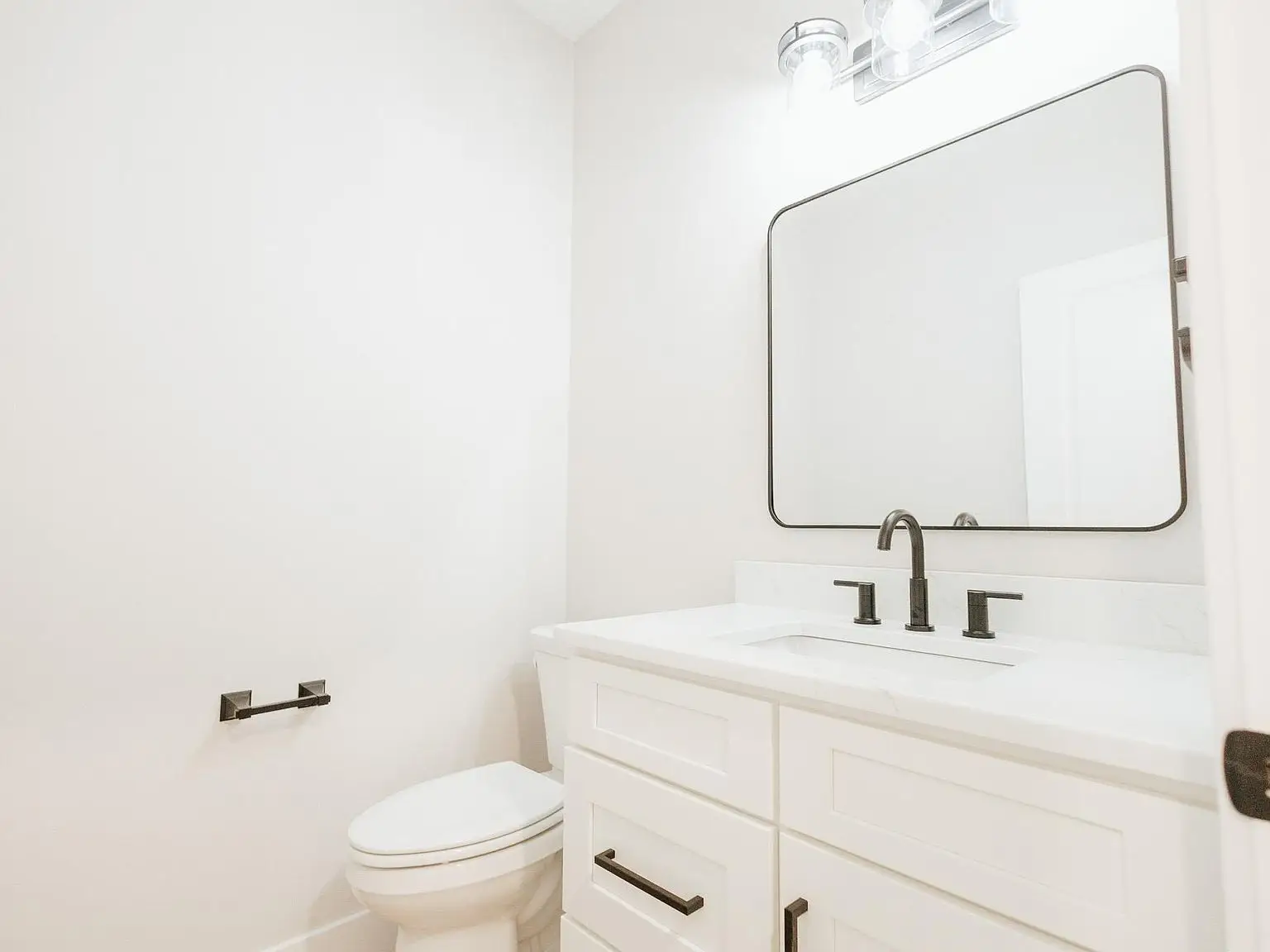Modern bathroom in the Asher floor plan with white walls, vanity, and sleek black fixtures.