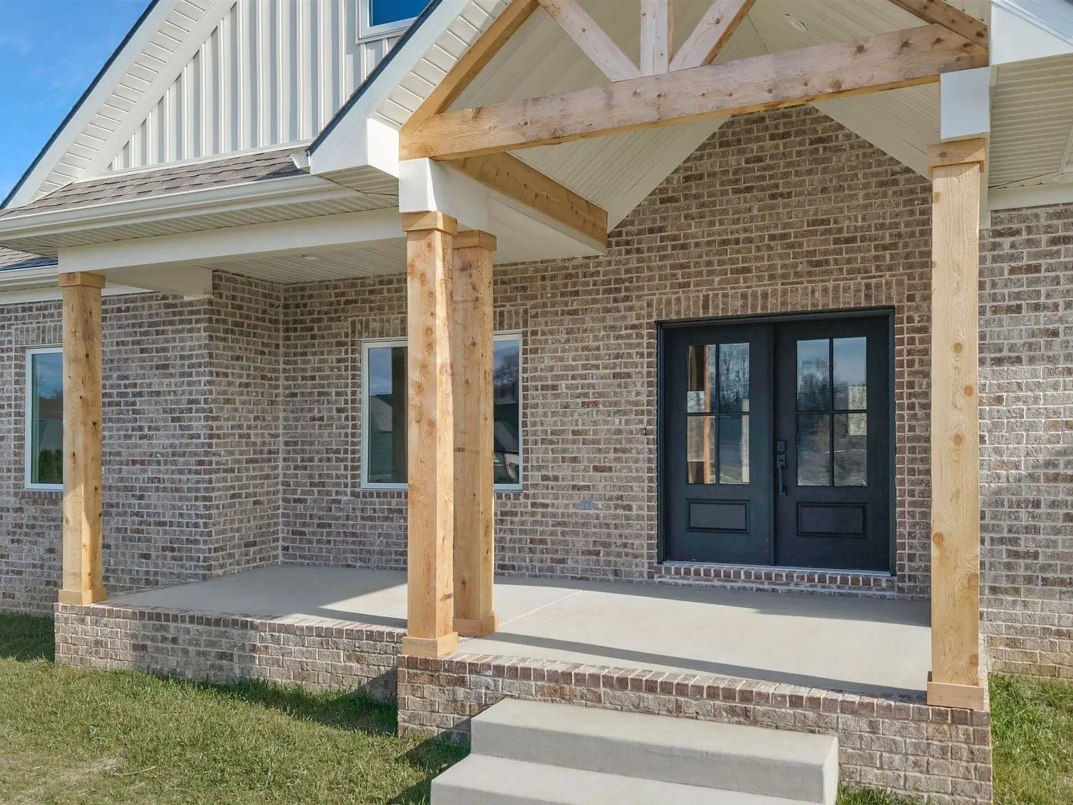 Brick house with Ava floor plan, wooden porch columns, and black double front doors.