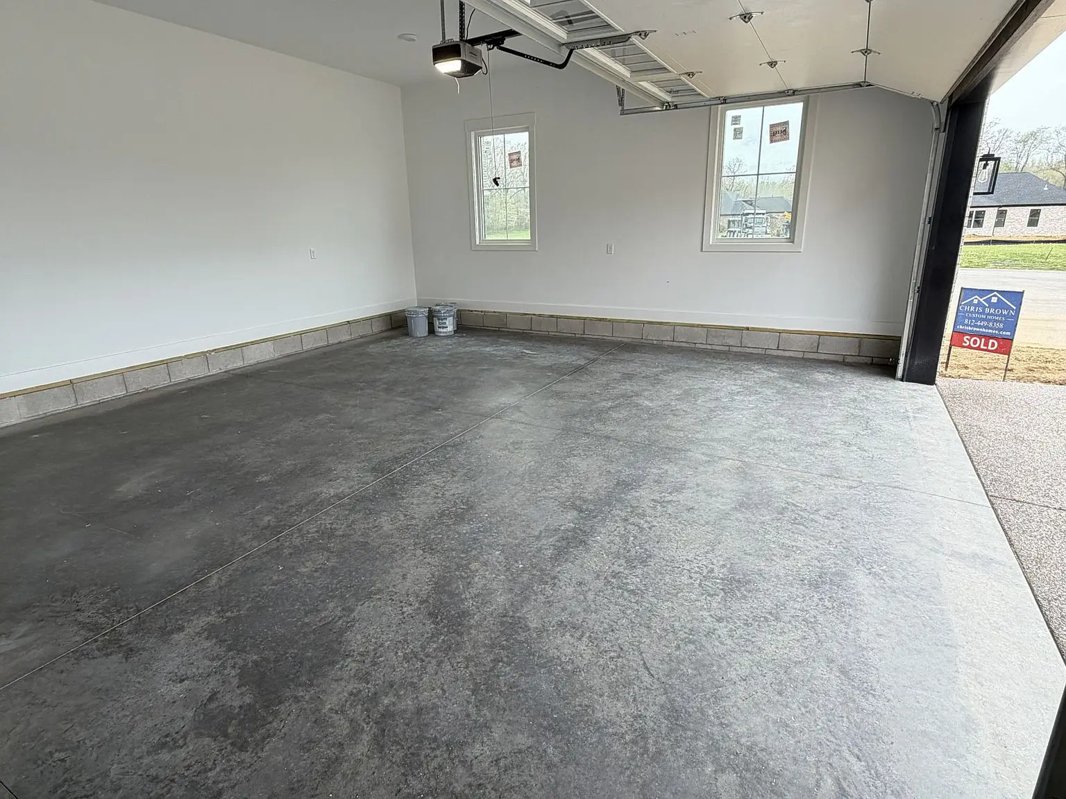 Empty two-car garage with concrete floor, Robin floor plan, two windows, and Chris Brown Homes sign.