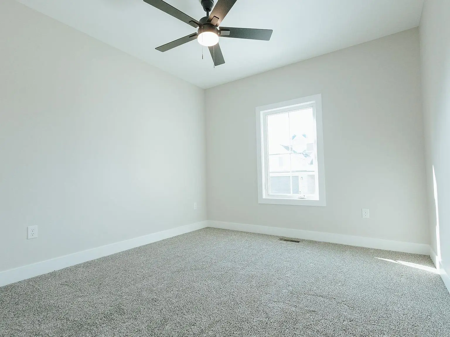 Empty room in the Asher floor plan with gray carpet, white walls, window, and ceiling fan.