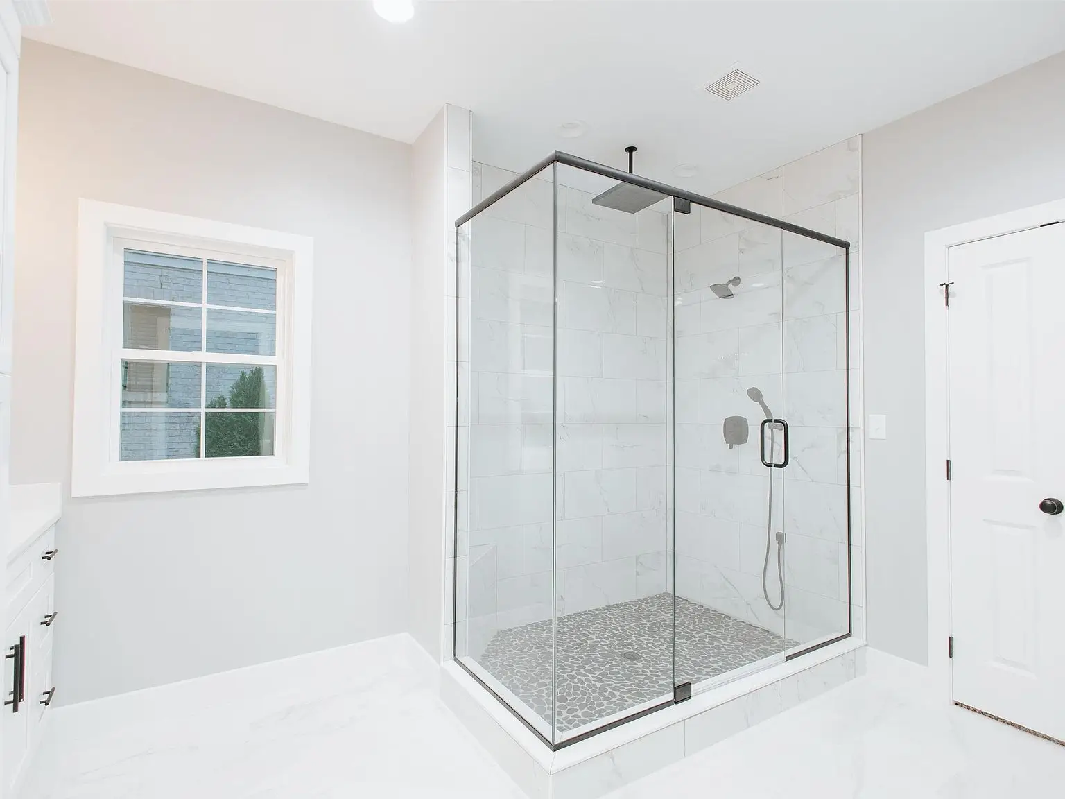 Modern bathroom with glass-enclosed shower, white walls, and a window—Eleanor floor plan.
