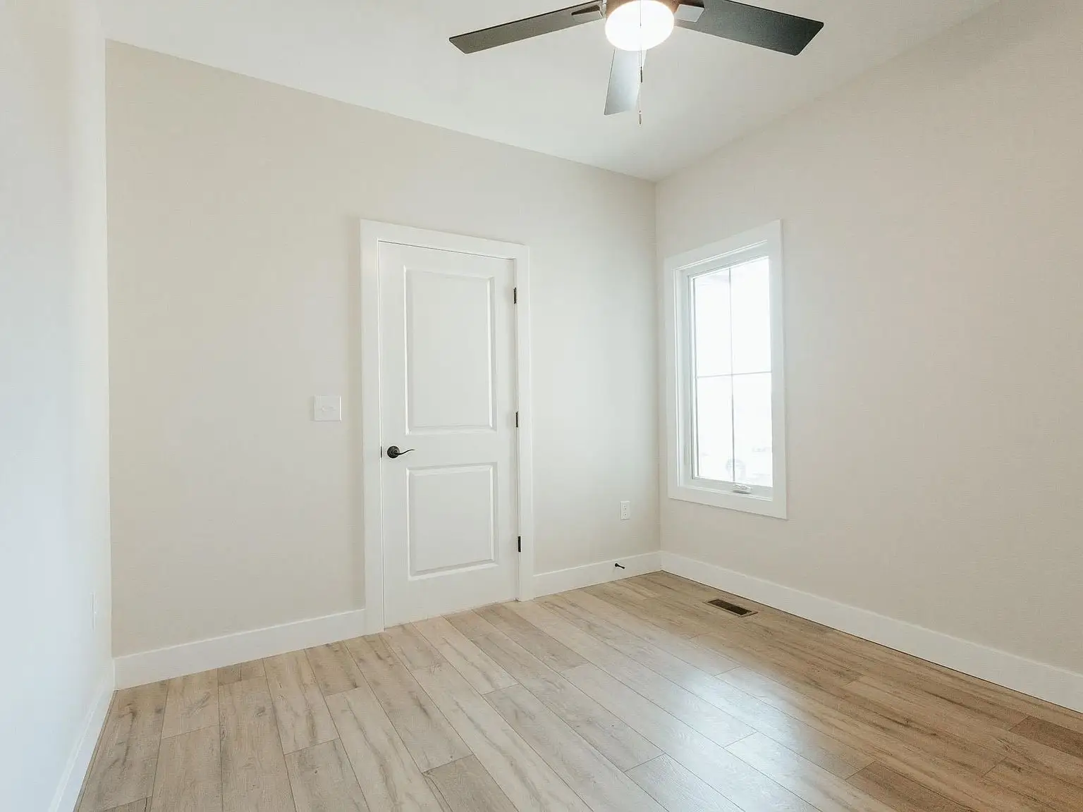 Empty room with light wood floor from the Asher floor plan by Chris Brown Homes 18801 Roscommon Rd.