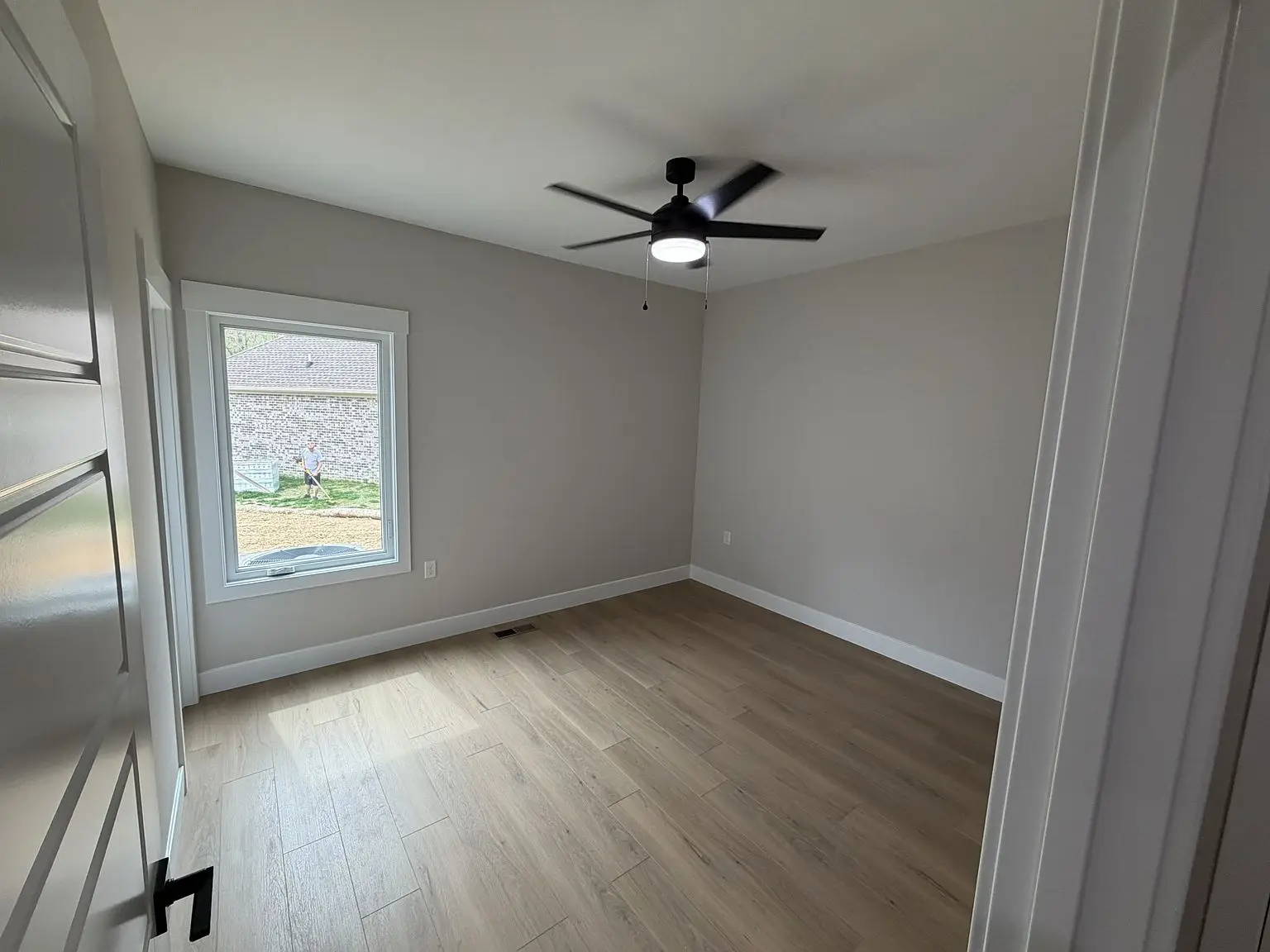 Empty room with light wood floor, gray walls, window; Robin floor plan by Chris Brown Homes.